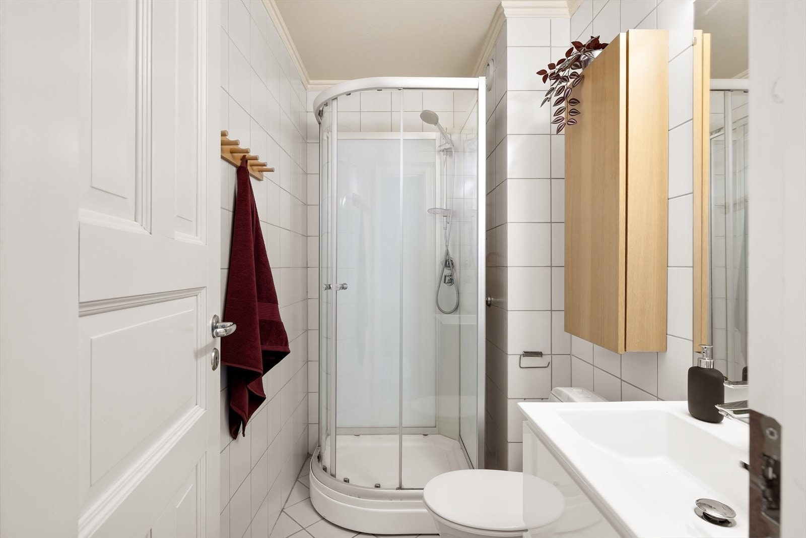 Flislagt bad med lyse fliser på vegger og gulv, samt elektriske varmekabler Galleribilde