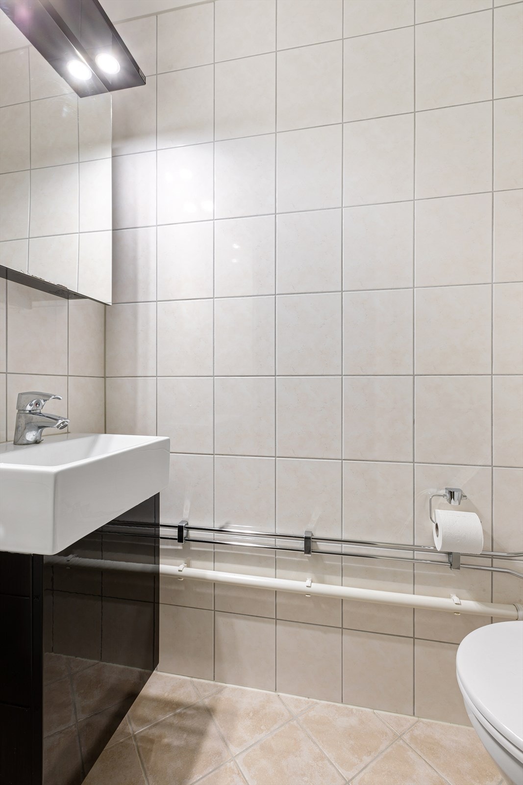 Praktisk wc rom fra 2014 med klosett og servantinnredning med speilskap og integrerte downlights Galleribilde