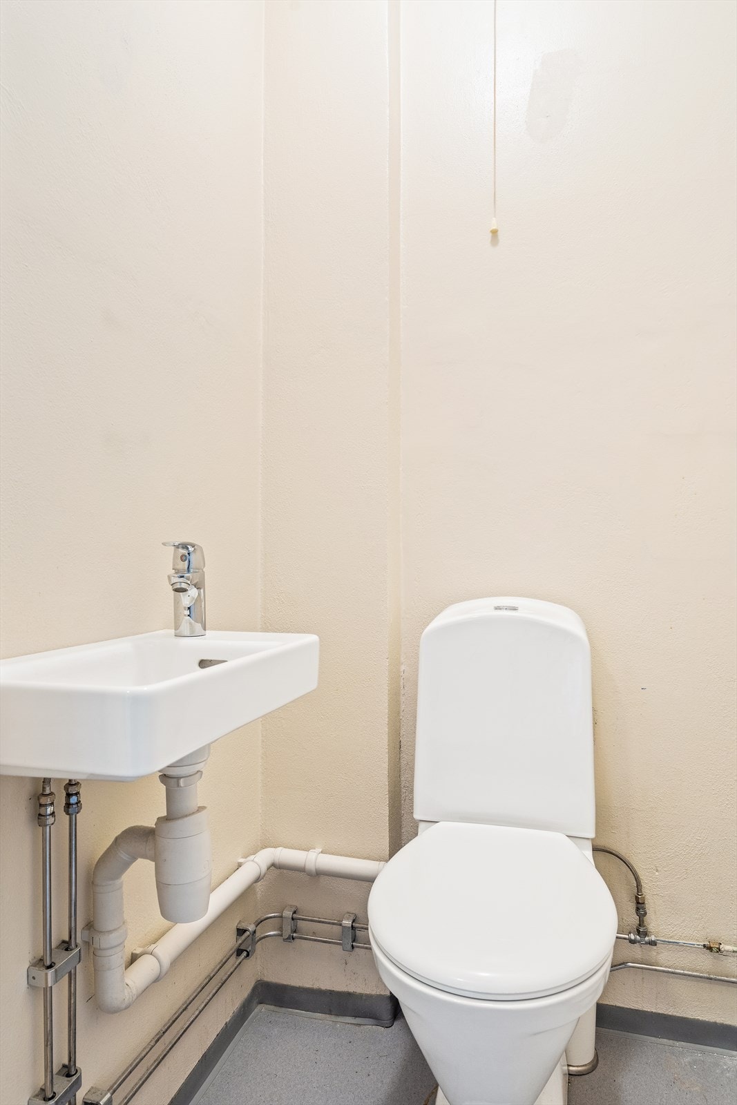 Leiligheten har et separat wc-rom av enkel utførelse. Rommet er innredet med toalett og servant. Servant er ikke standard i disse leilighetene, men ble her montert i 2019. Galleribilde