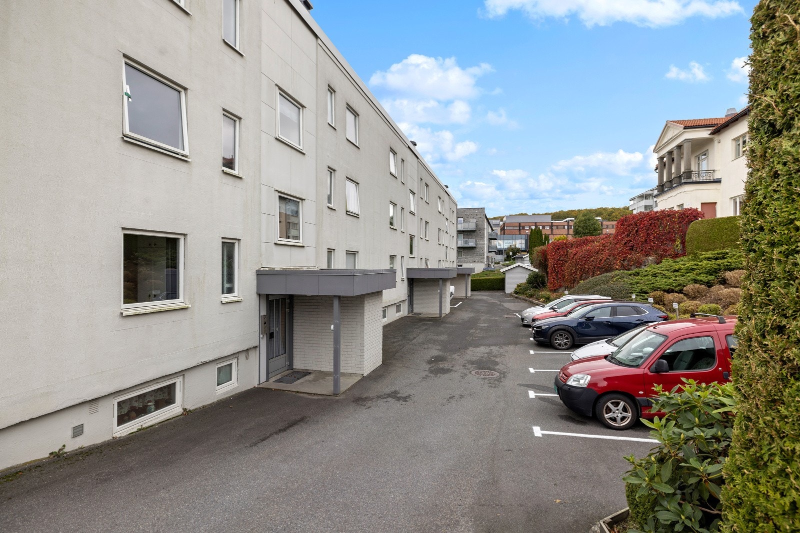 Fellestomten er opparbeidet med asfalterte parkeringsområder, velfrisert hekk og vintergrønne prydbusker. Galleribilde