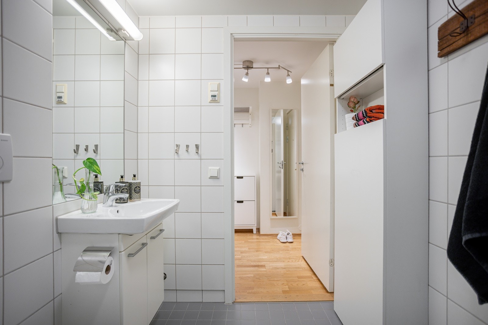 Baderommet har grå fliser på gulv med gulvvarme, hvite fliser på veggene og avtrekksventil i himlingen. Galleribilde