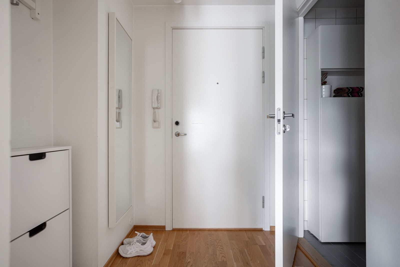 Entréen har parkett på gulv, glatte lysmalte overflater og skjult elektrisk anlegg. Montert porttelefon på vegg ved ytterdøren. Galleribilde