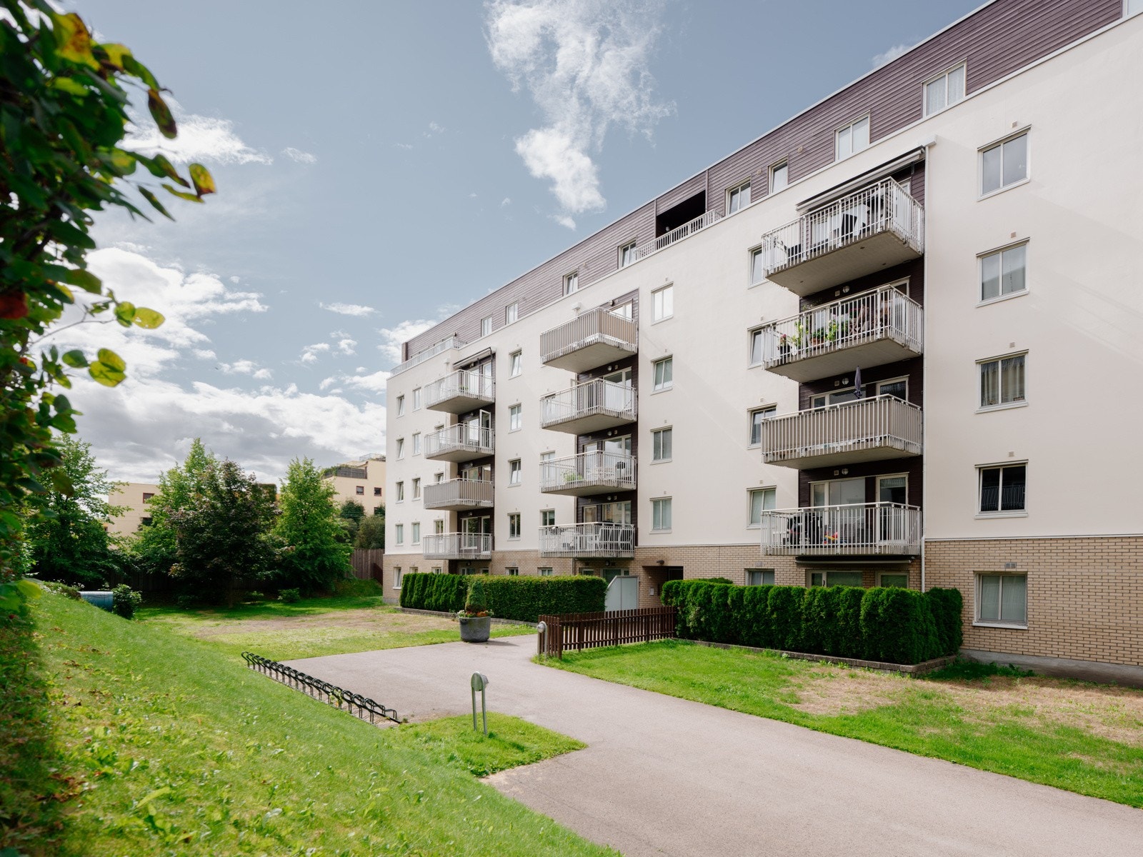 Tomt opparbeidet med busker, trær, diverse beplantning, plenområder, sittegrupper og asfalterte internveier. Galleribilde