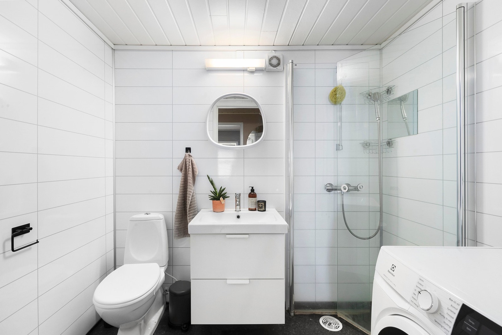 Baderom med gulvvarme, innfellbare dusjdører, opplegg for vaskemaskin, wc, servant, servantskap og mekanisk avtrekk. Galleribilde