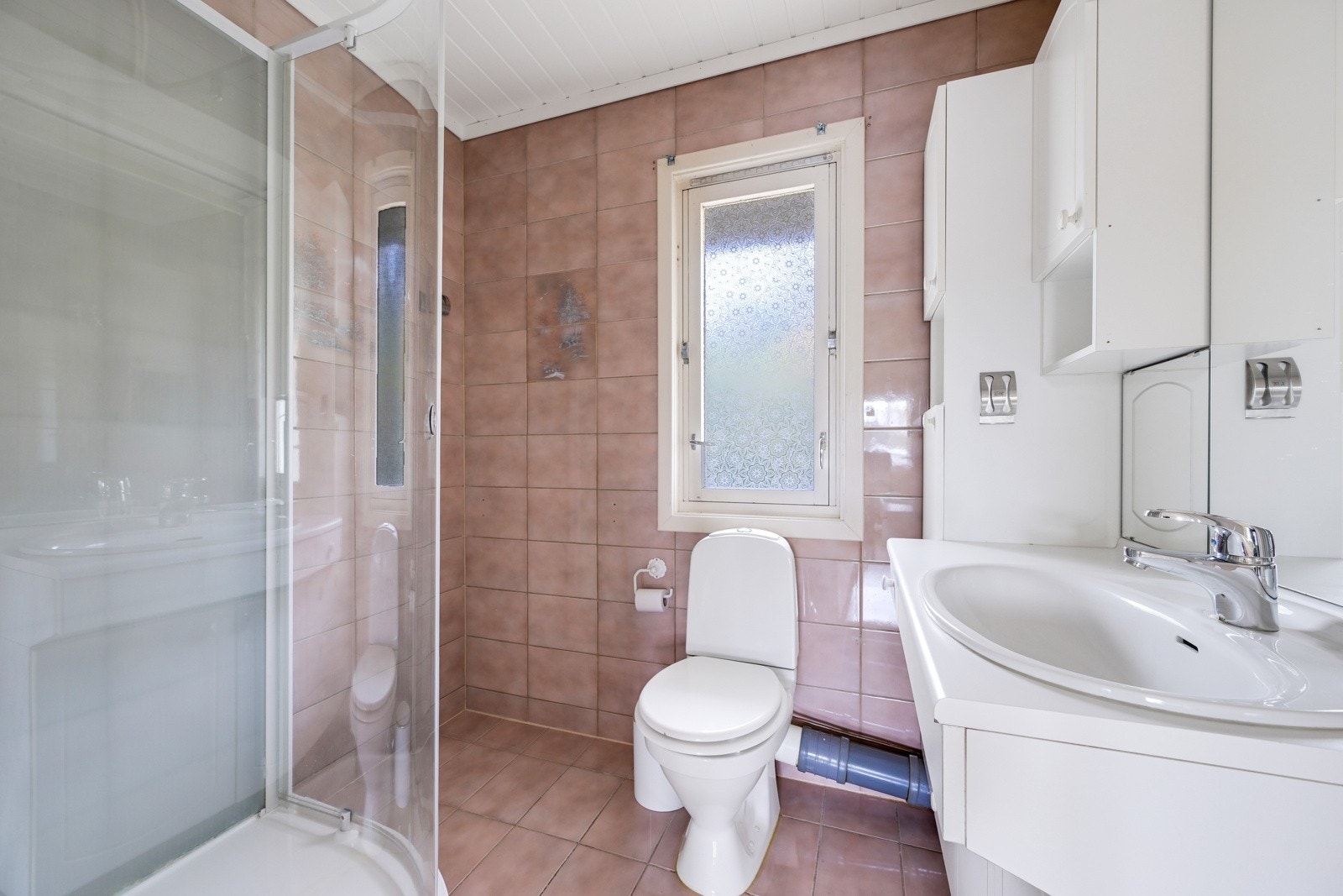 Baderommet er av eldre type med dusjkabinett, klosett og servant med en eldre innredning Galleribilde