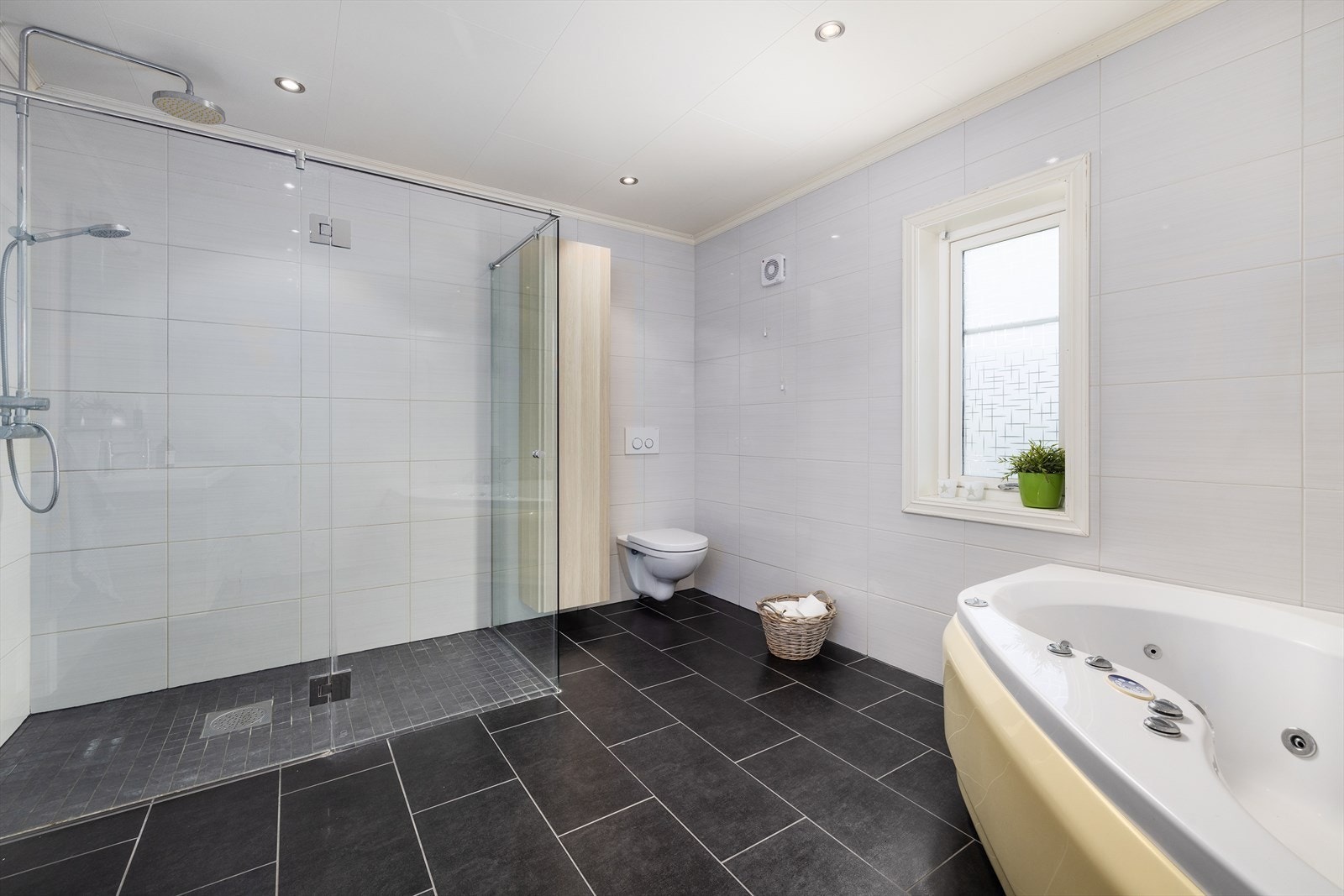 Badet er innredet med servant, vegghengt toalett, boblebad og stor dusjnisje/hjørne. Galleribilde