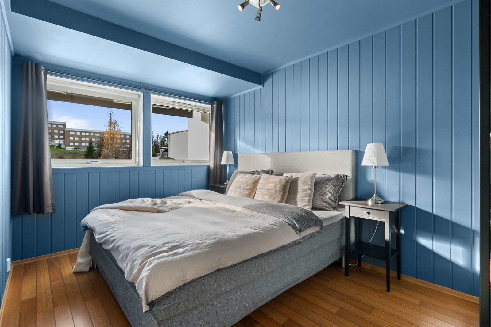 Soverommet er malt i en dus blå farge og har to store vinduer. Det er god plass til seng, nattbord og andre møbler. Galleribilde