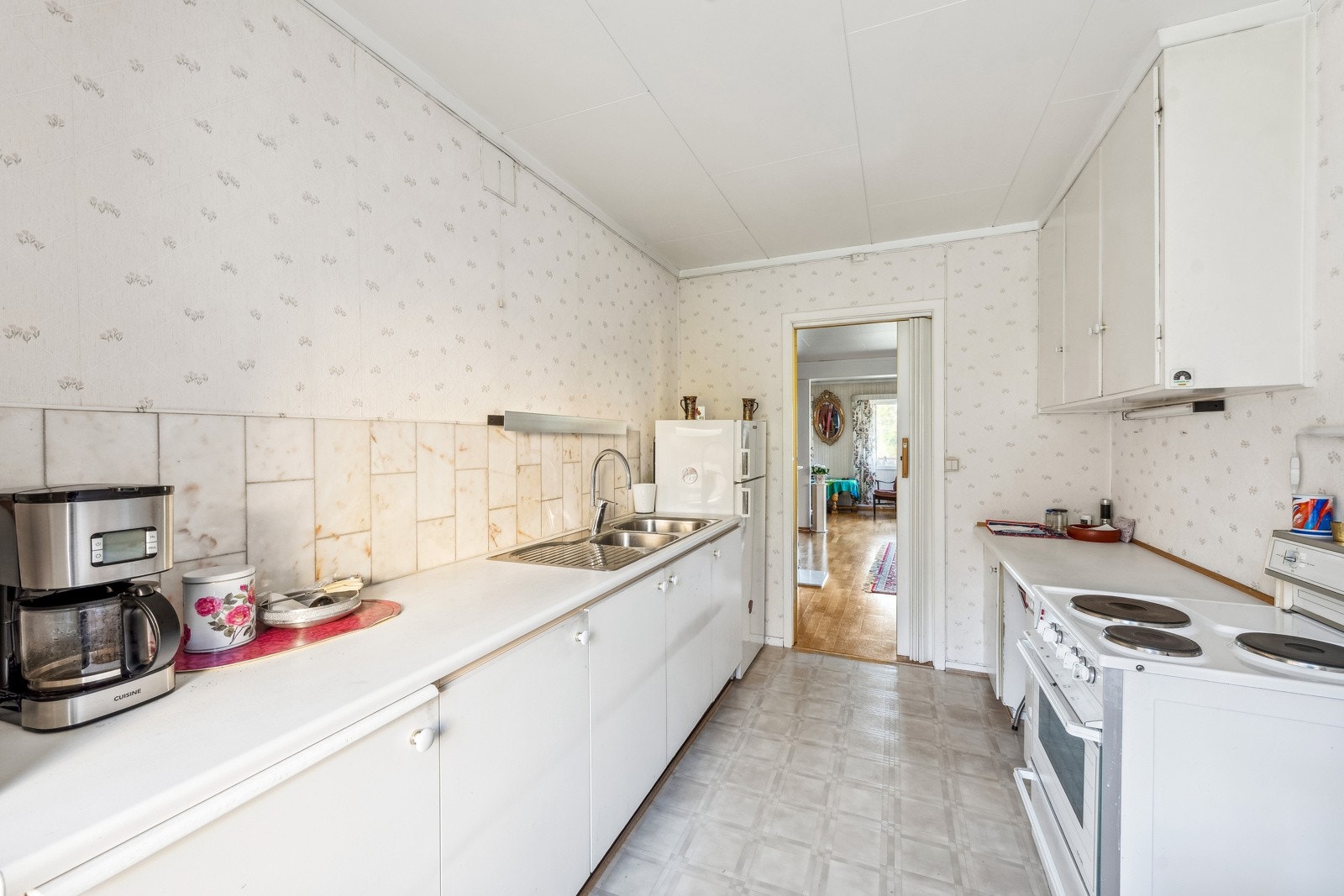 Kjøkkeninnredning med slette fronter og benkeplater av laminat. Dobbelt nedfelt oppvaskkum i rustfritt stål med ett-greps armatur. Fliser på vegg samt belysning og stikkontakt på vegg over kjøkkenbenk. Galleribilde