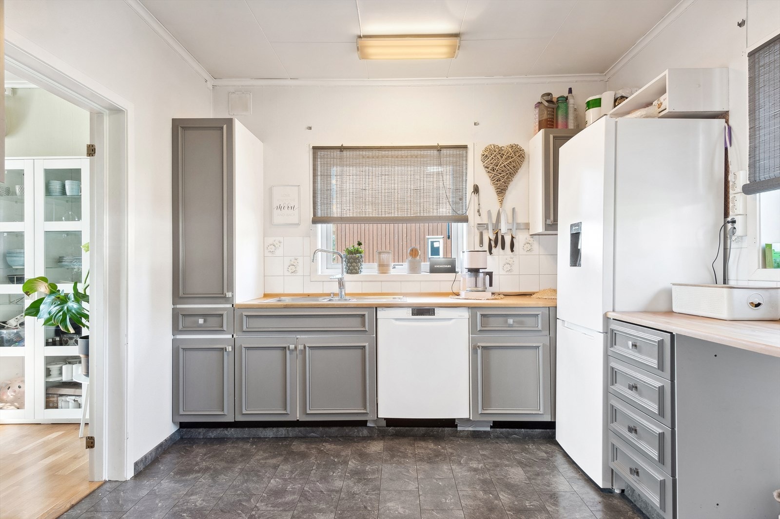 Kjøkkeninnredningen er godt utbygget med over- og underskap, med profilerte fronter. Heltre benkeplate med god arbeidsplass og rustfri oppvaskkum med fliser i benkerygg. Galleribilde