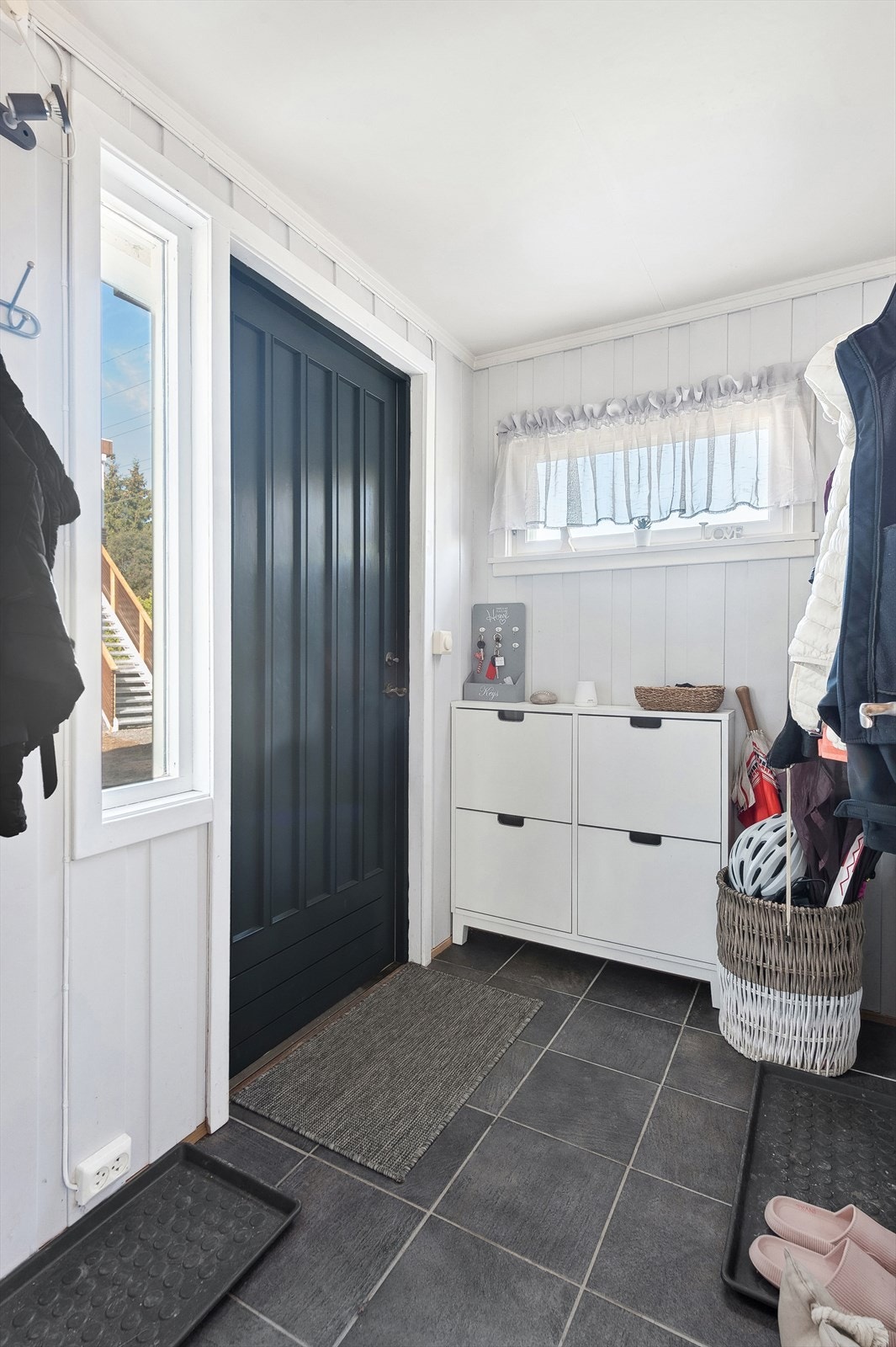 Du ønskes velkommen inn i en flislagt entré med plass til å henge fra yttertøy og sette fra seg skoene. Galleribilde