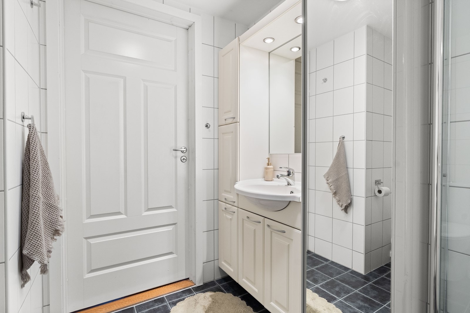 Badet inneholder speilinnredning med lys, toalett og dusj i hjørne bak svingbare glassvegger. Galleribilde