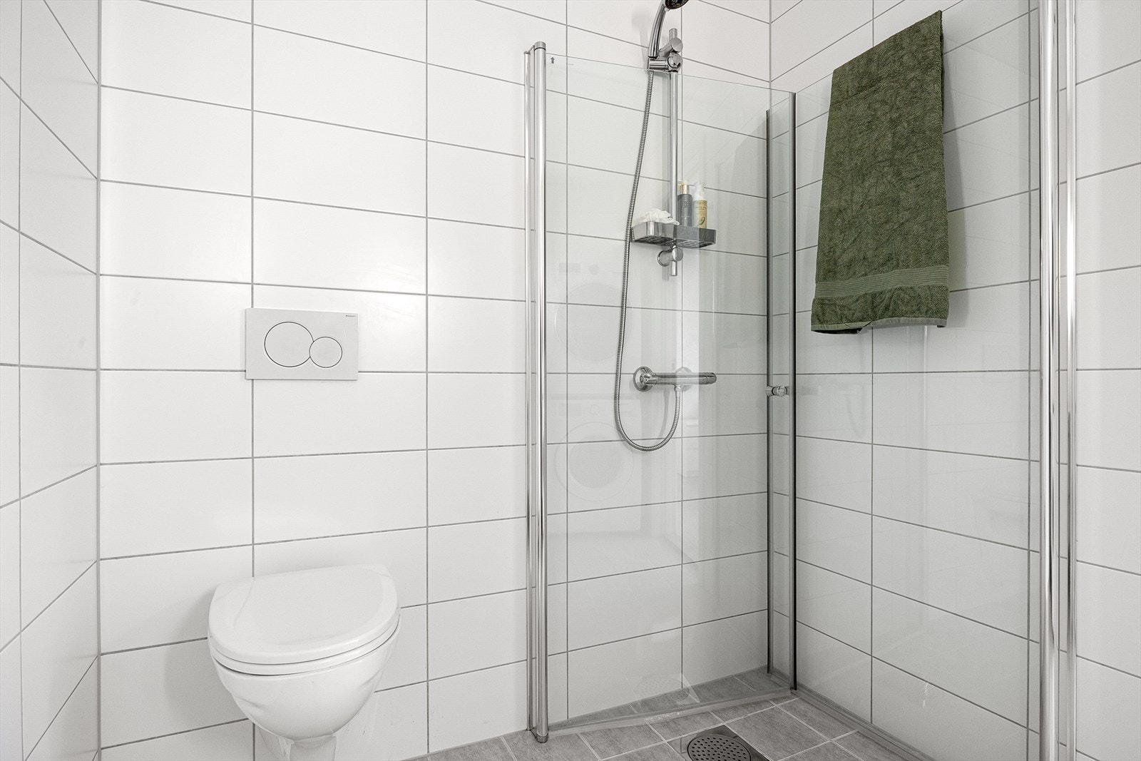 Boligen har et romslig og praktisk innredet bad som er utstyrt med vegghengt toalett, dusj med glassfoldedører, samt en servant med møblement, speil og belysning. Galleribilde
