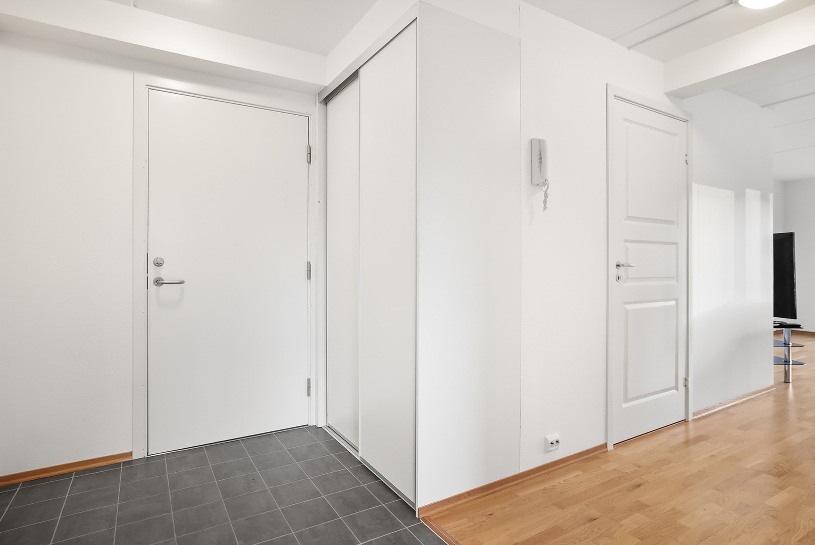 Lys entrè med skyvedørsgarderobe for oppbevaring av klær. Galleribilde