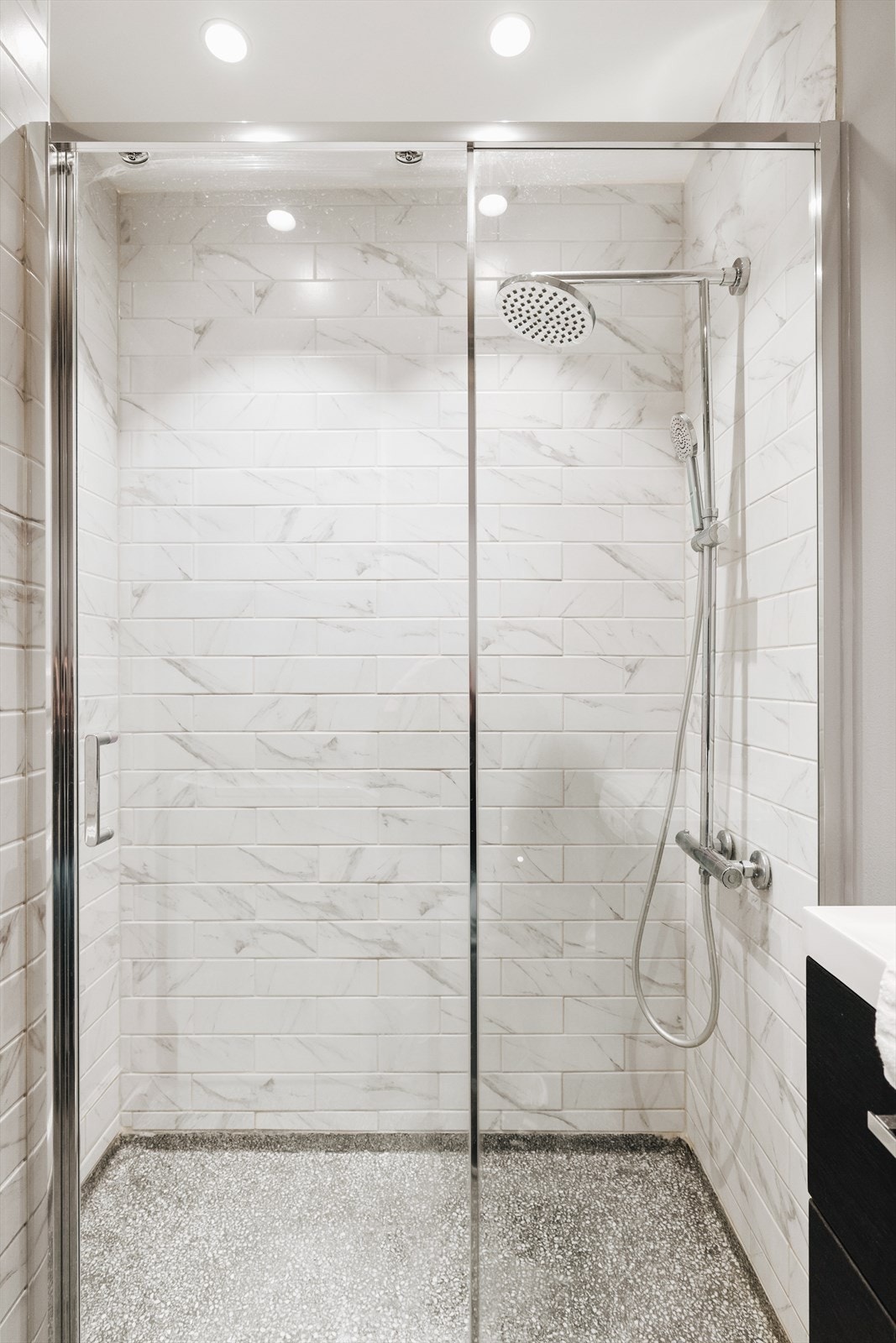 Helfliset dusjhjørne i nydelige fliser, med en fin skjermvegg og skyvedør i glass Galleribilde