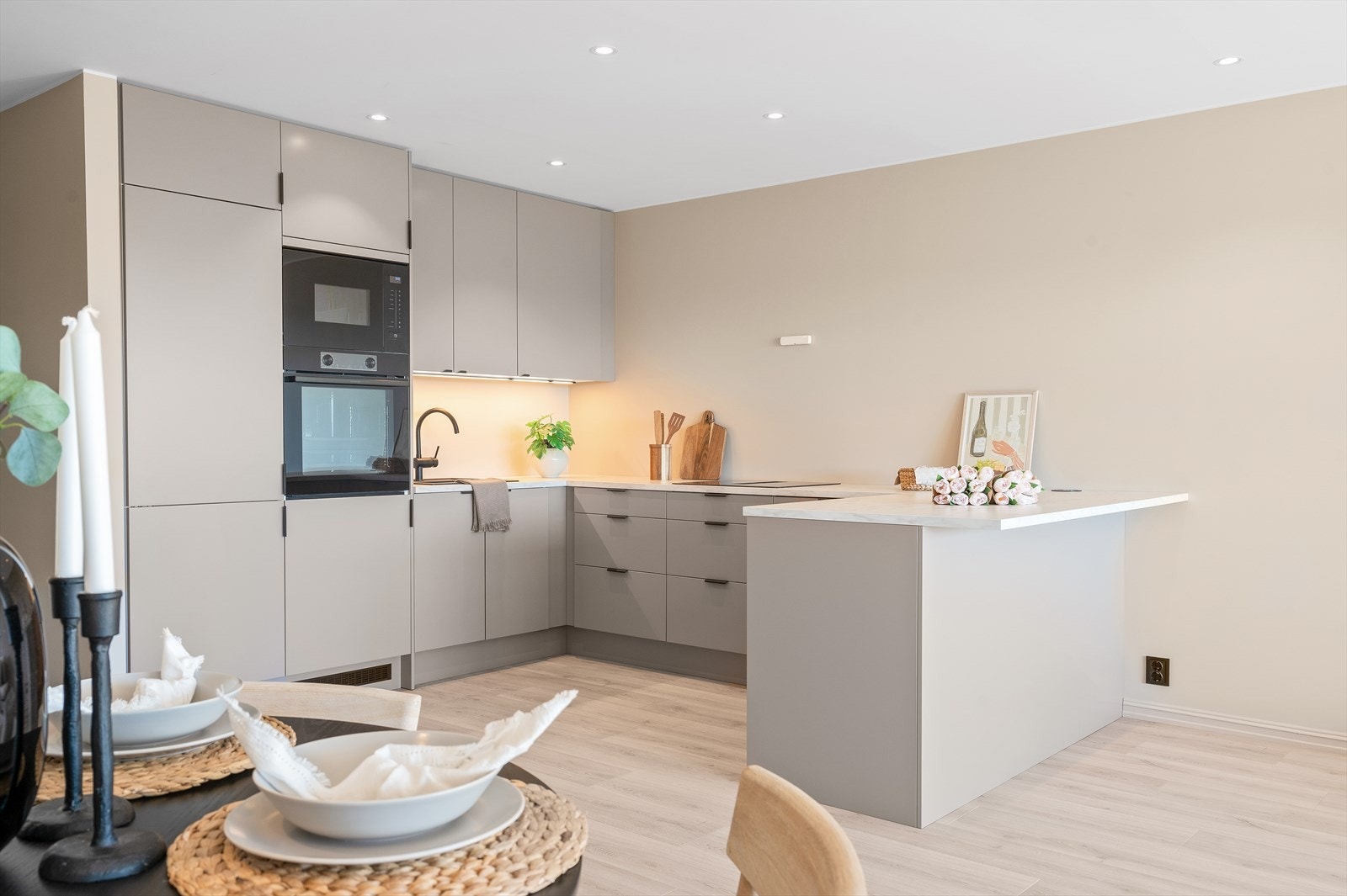 Det moderne kjøkkenet har lyse, slette fronter og belysning under overskapene. Galleribilde