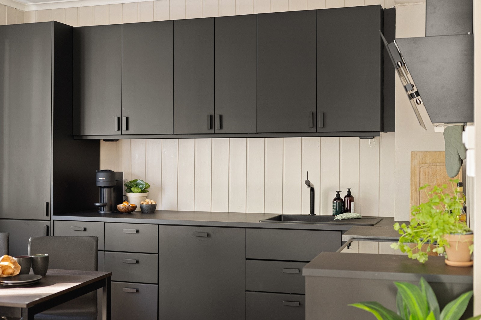 Innredningen har sorte glatte fronter og laminert benkeplate med nedfelt sort oppvaskkum. Praktisk med belysning og stikkontakter under overskap. Galleribilde