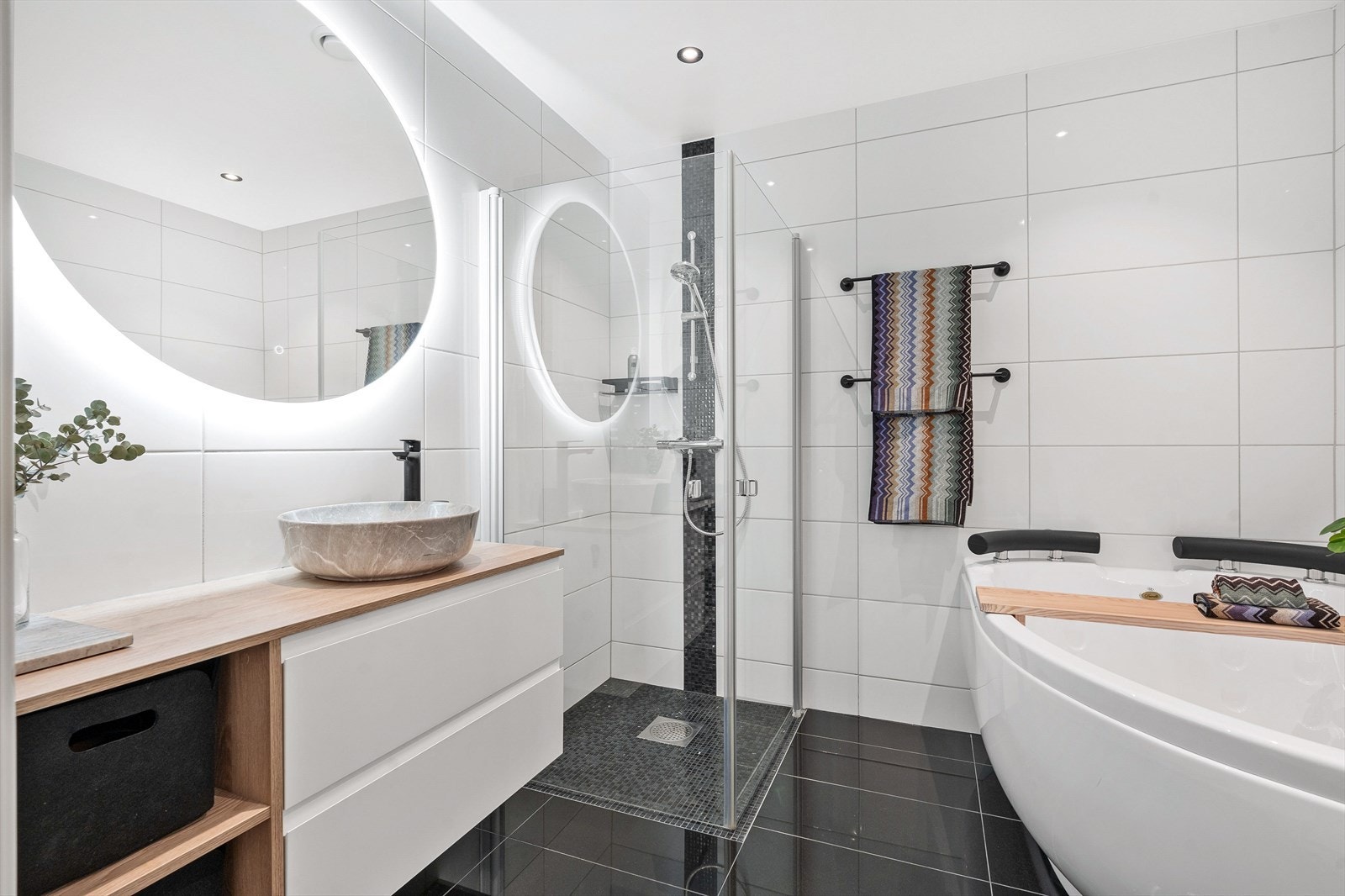 Delikat baderom med dusj, badekar, servant i møbel og vegghengt toalett. Galleribilde