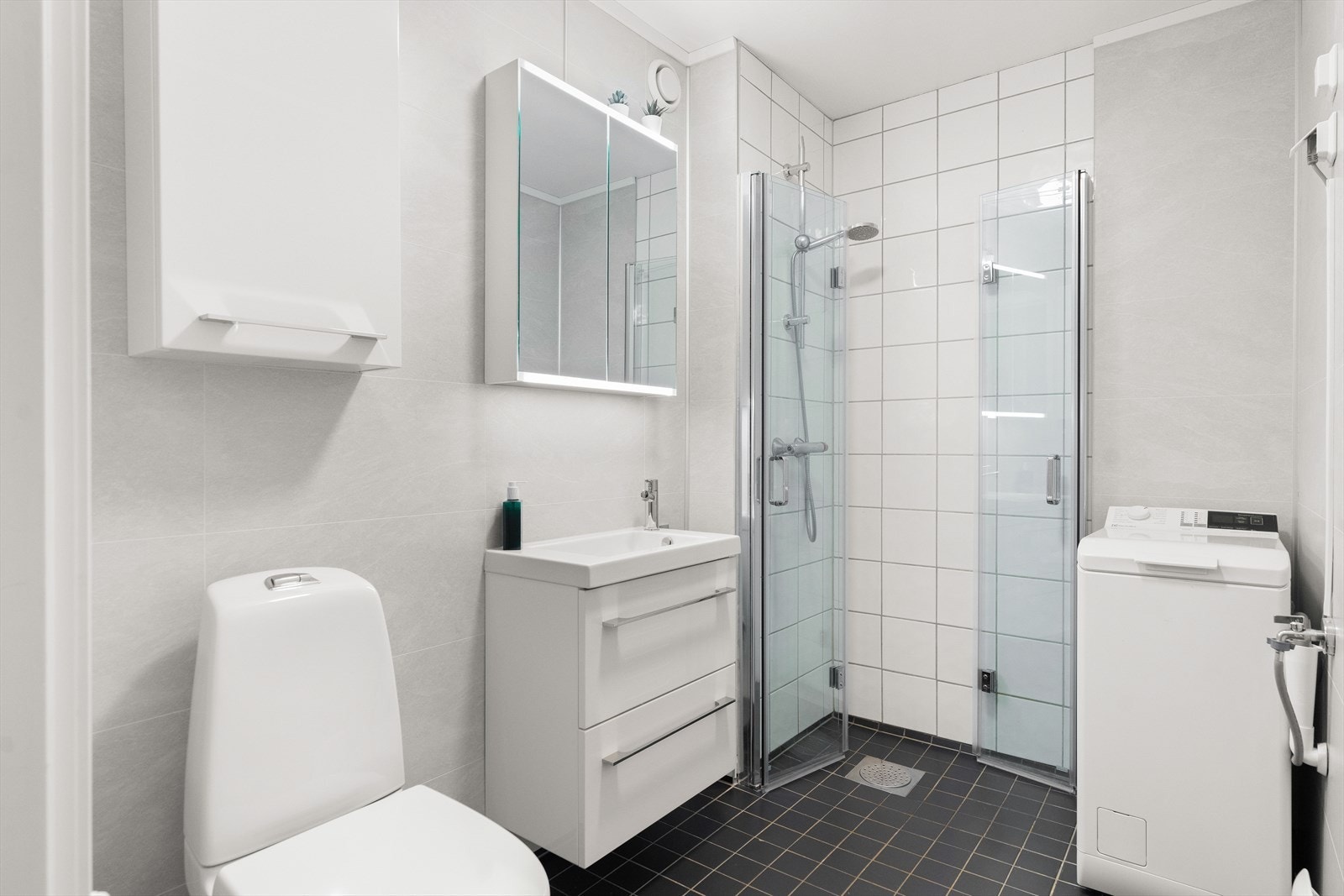 Fra gangen er det inngang til badet. Rommet har flislagt gulv, fliser i dusjsonen og våtromspanel på øvrige vegger samt malt slett himling. Galleribilde