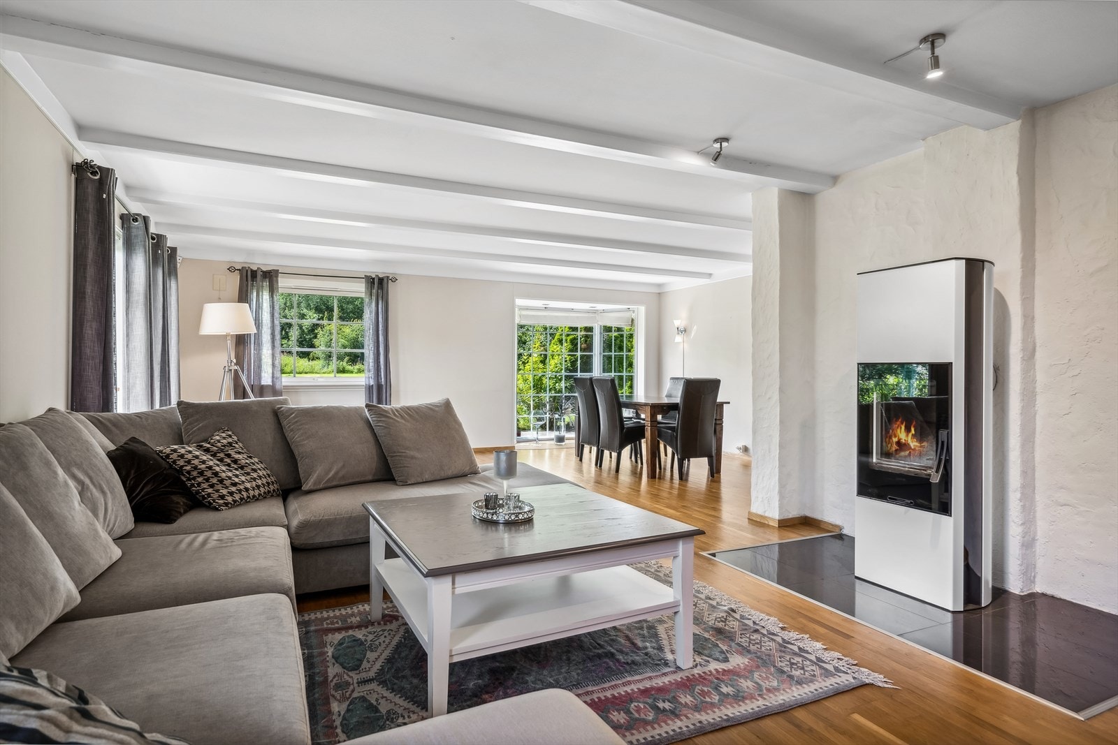 Stuen er lys og hyggelig, med synlige bjelker i himlingen og en fin vedovn med stort flammebilde. Galleribilde