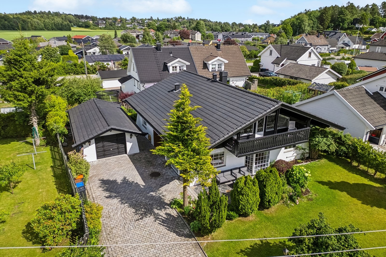 Oversiktsbilde over eiendommen. Det er flere biloppstillingsplasser foran garasjen. Galleribilde