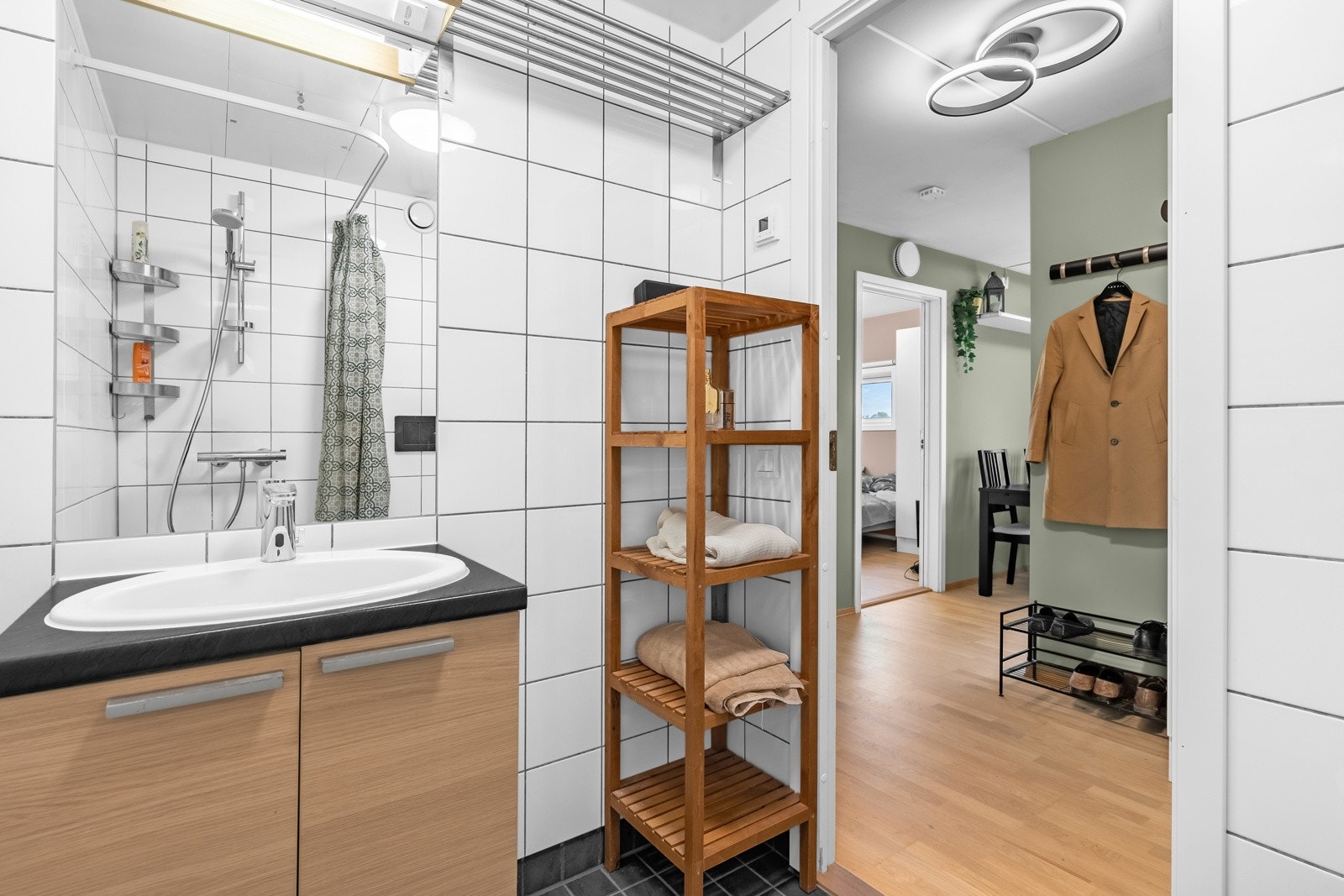 Badet ble oppgradert i 2024 med kontaktløst armatur med bevegelsessensor, toalett med spyleknapp samt dusjarmatur. Baderommet inneholder servant med underskap, speil med overbelysning, vegghengt toalett og dusjhjørne. Galleribilde