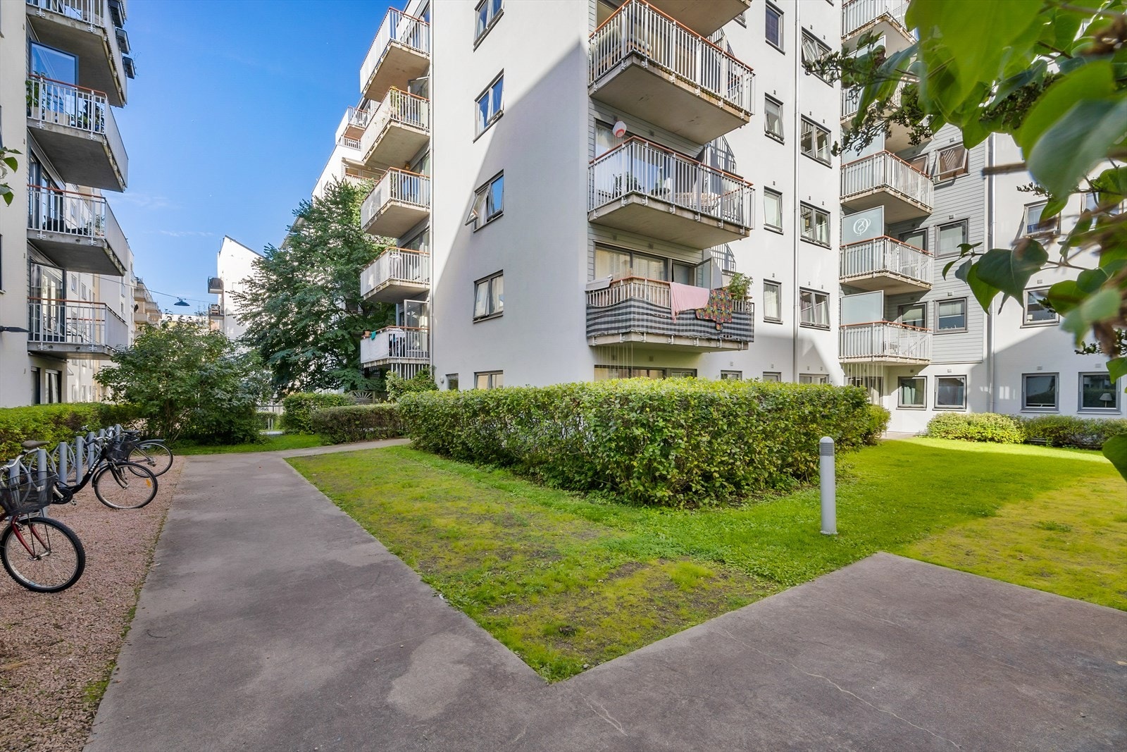 Pene fellesarealer med asfalterte gangveier, gressplen og beplantning omkranser bygget. Galleribilde