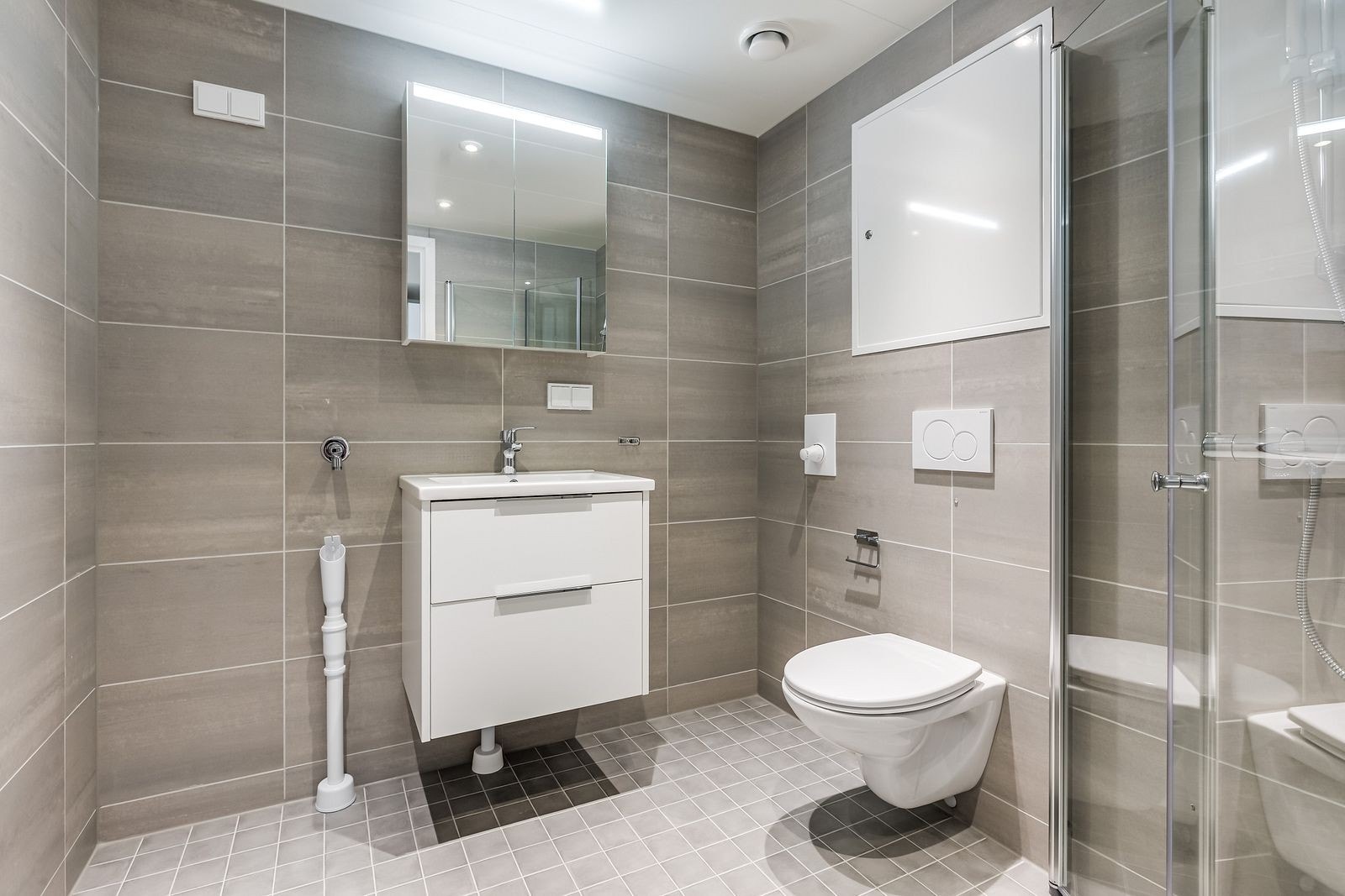 Flislagt bad med dusjhjørne og opplegg til vaskemaskin Galleribilde