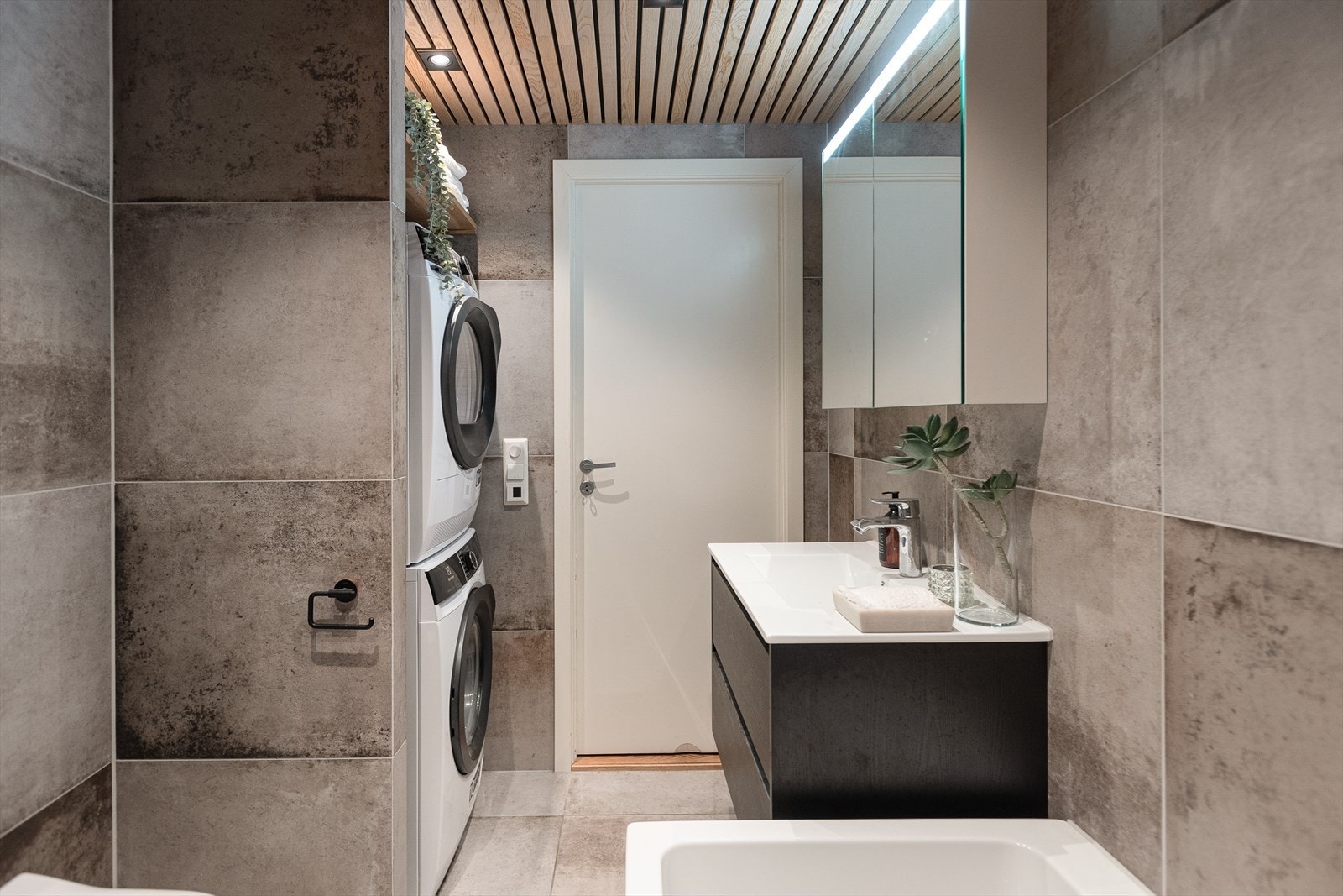 Det er utstyrt med badekar, dusjhjørne, innfellbare dusjdører, naturlig avtrekk, servant og servantskap, samt opplegg for vaskemaskin. Galleribilde