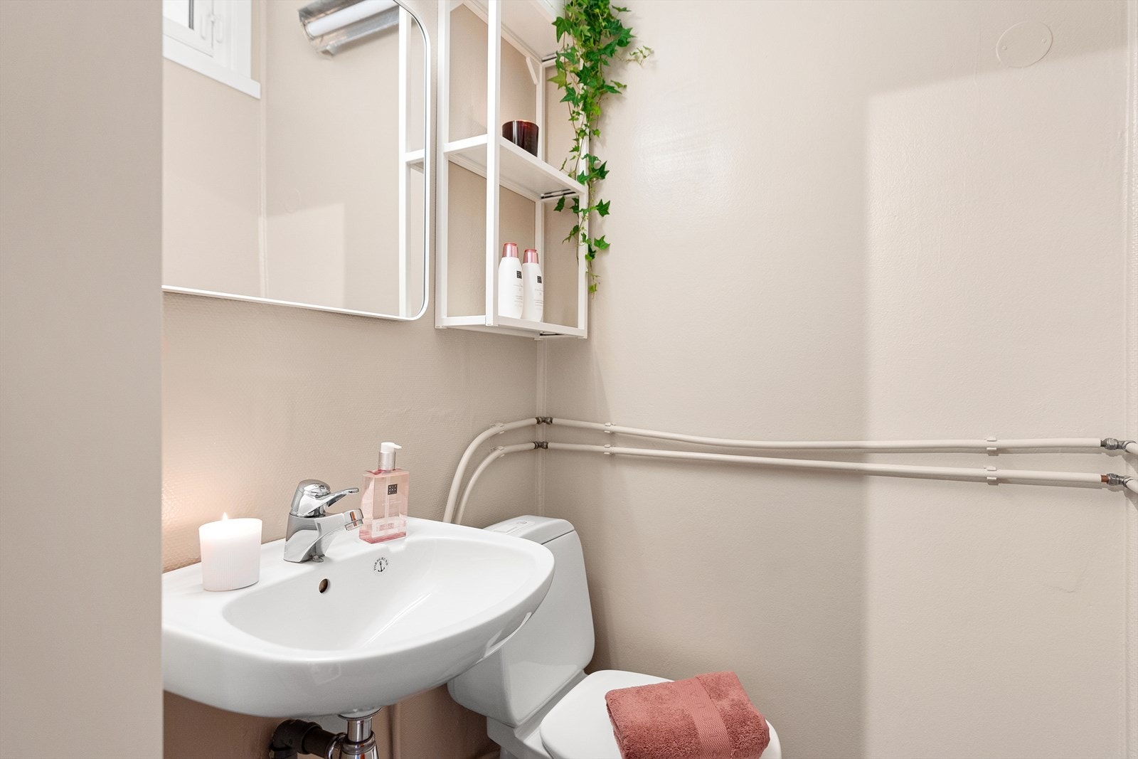 Badet inneholder: Servant, speil og belysning, ett høyskap, toalett, dusjgarnityr og avtrekksventil i vegg. Galleribilde