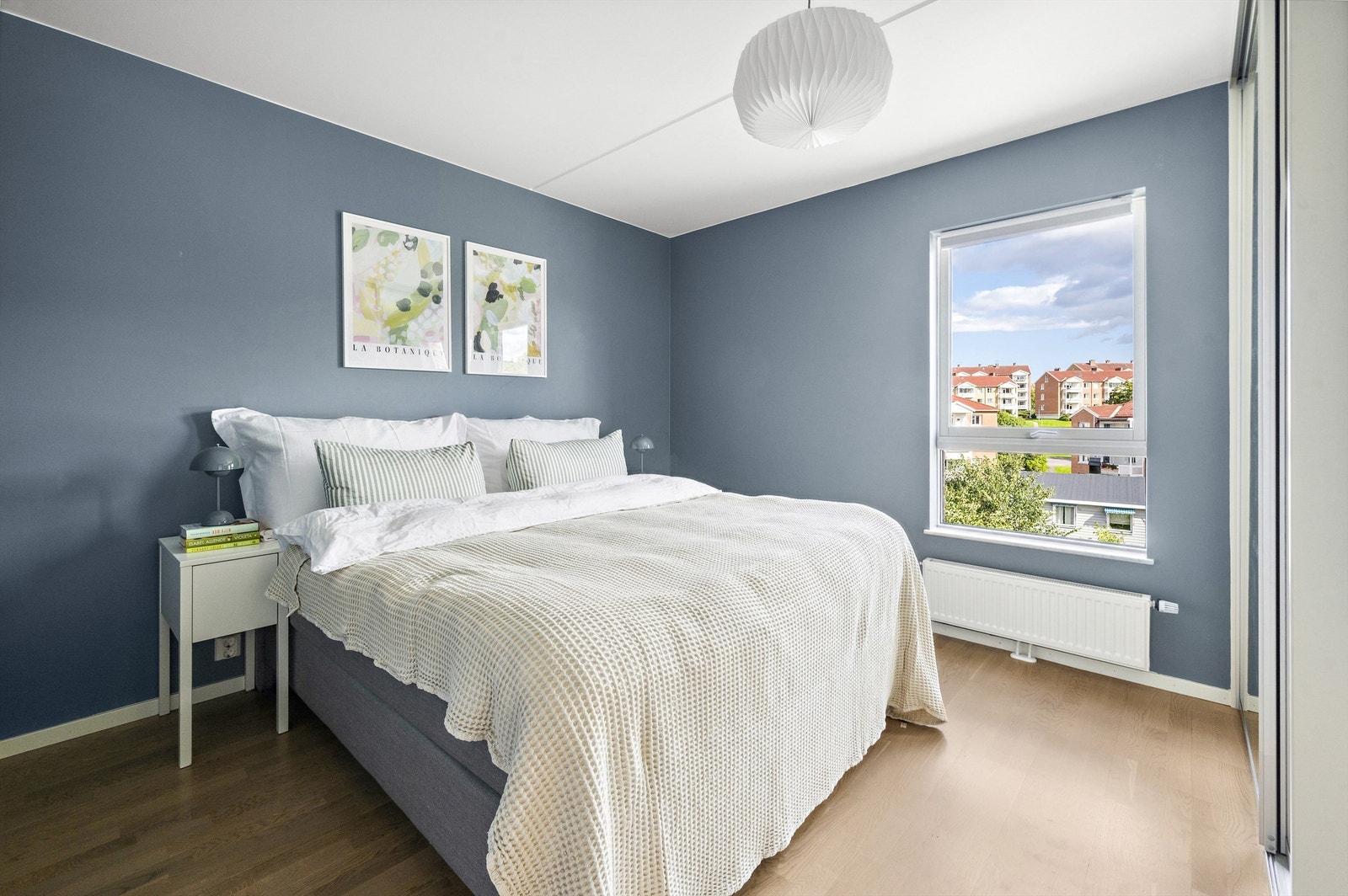 Masser av lysinnslipp fra et stort vindu som gjør rommet lyst og luftig - vinduskarmene i leiligheten er smale og pene med egen hylle i stein Galleribilde