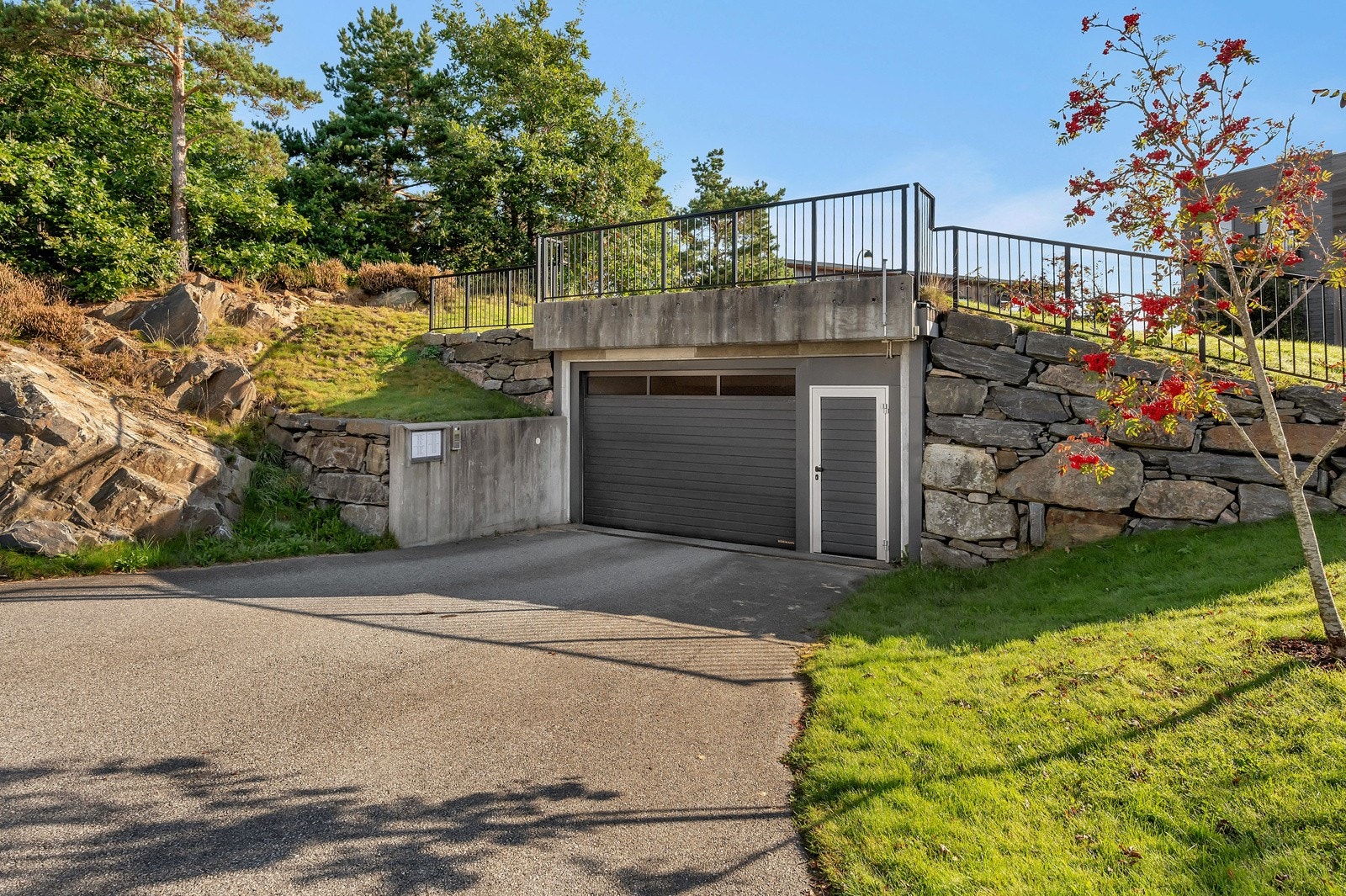 Innkjørsel til parkeringsplassene i lukket anlegg. Flere gjesteparkeringsplasser i parkeringskjelleren og ute på biloppstillingsplass Galleribilde