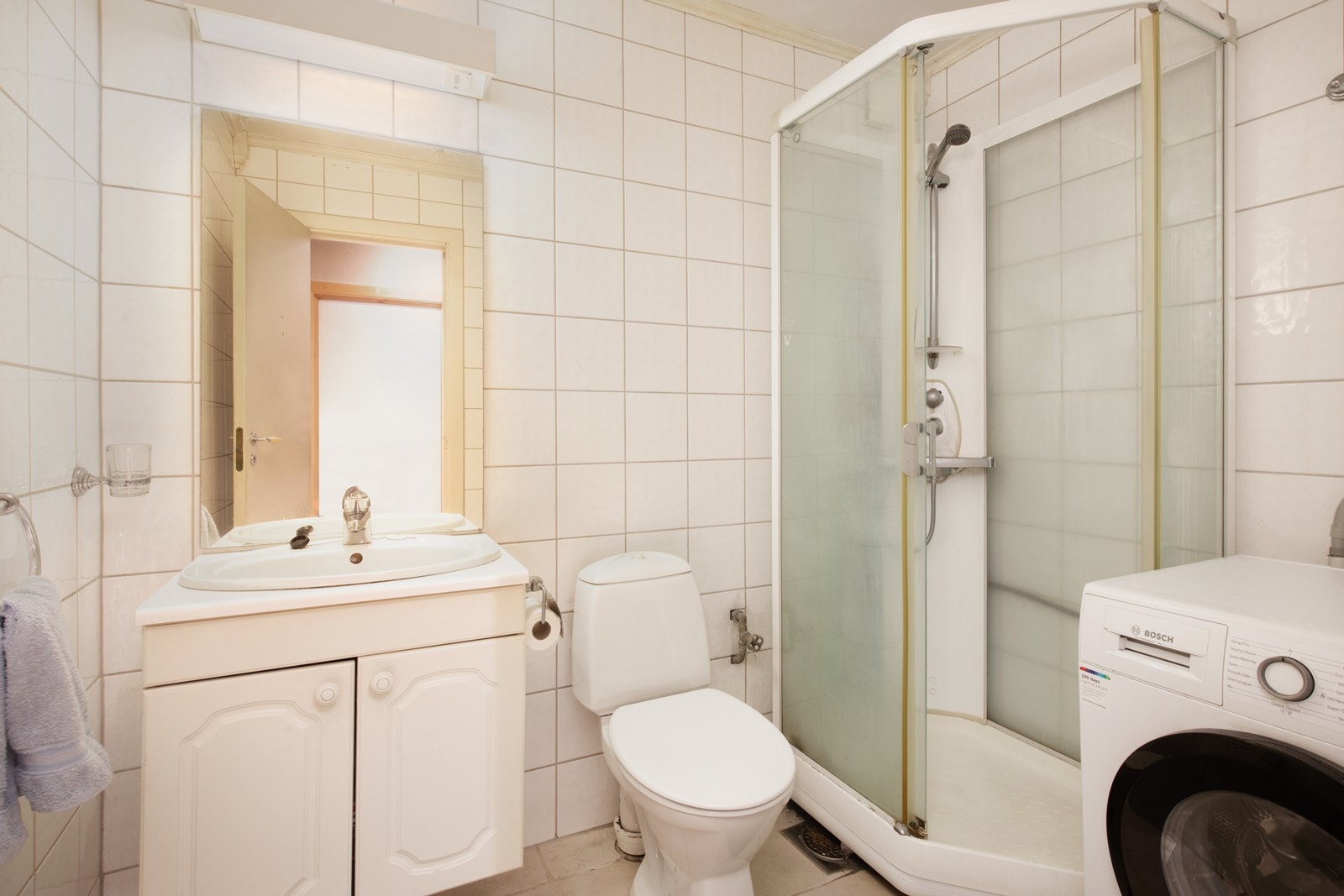 Flislagt bad som inneholder servant, dusjkabinett og wc Galleribilde