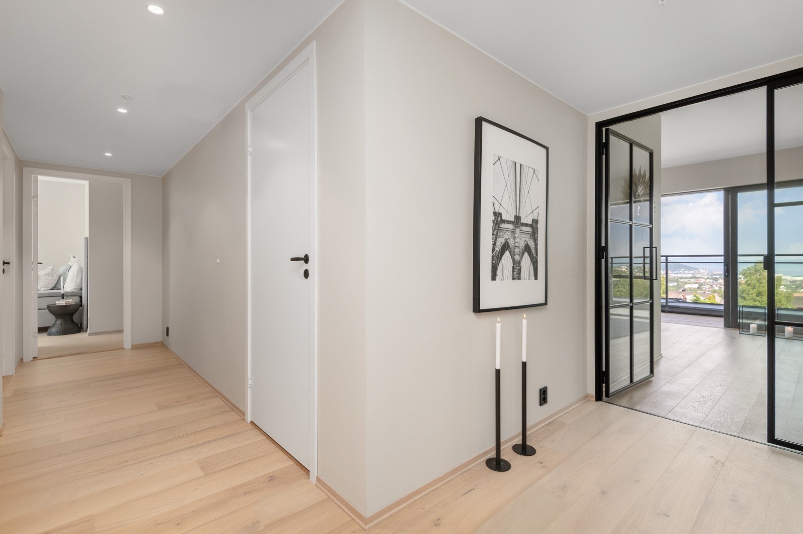 Lys og fin gang med sorte detaljer og downlights i tak. Porttelefon og heis i bygget. Galleribilde