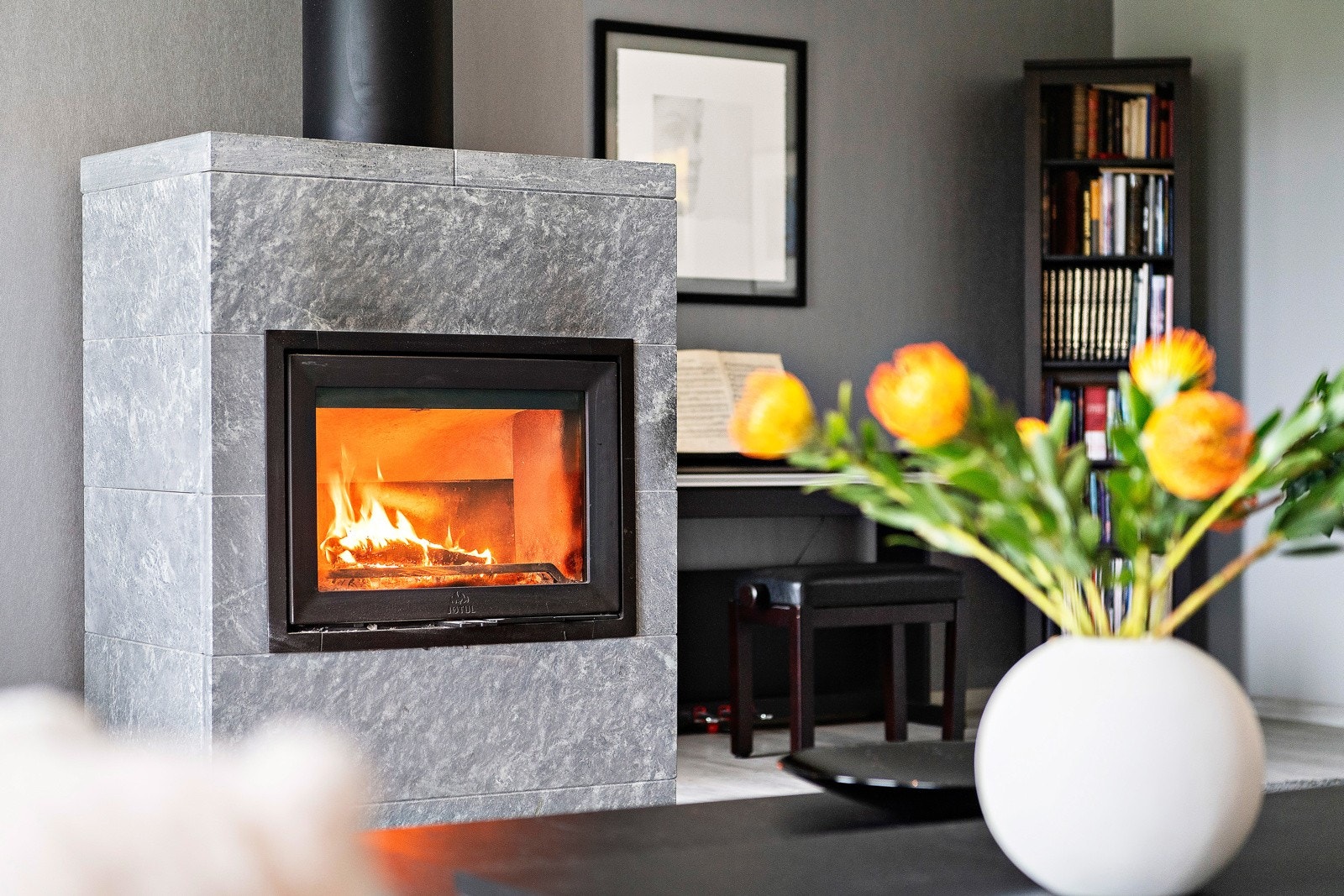 Stuen er utstyrt med en vakker vedovn som er dekorert med kleberstein. Klebersteinen holder godt på varmen og bidrar til en lun varme. Galleribilde