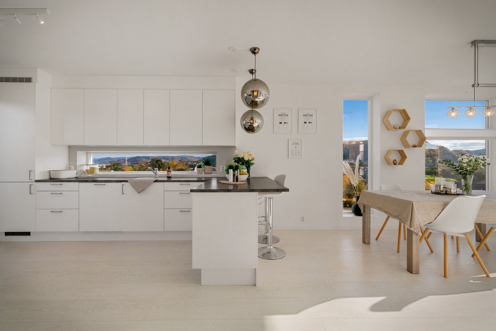 Stue/kjøkke preges av tidsriktige materialvalg og store vindusflater Galleribilde