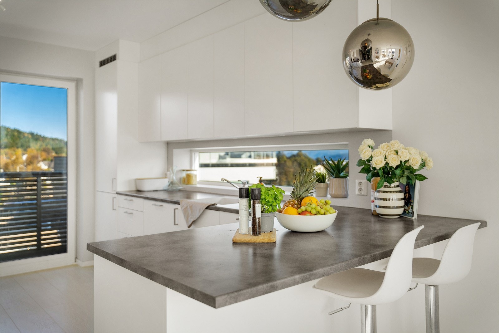 Kjøkkenet er praktisk utnyttet med store benkeflater med avsatt plass for bar-stoler Galleribilde