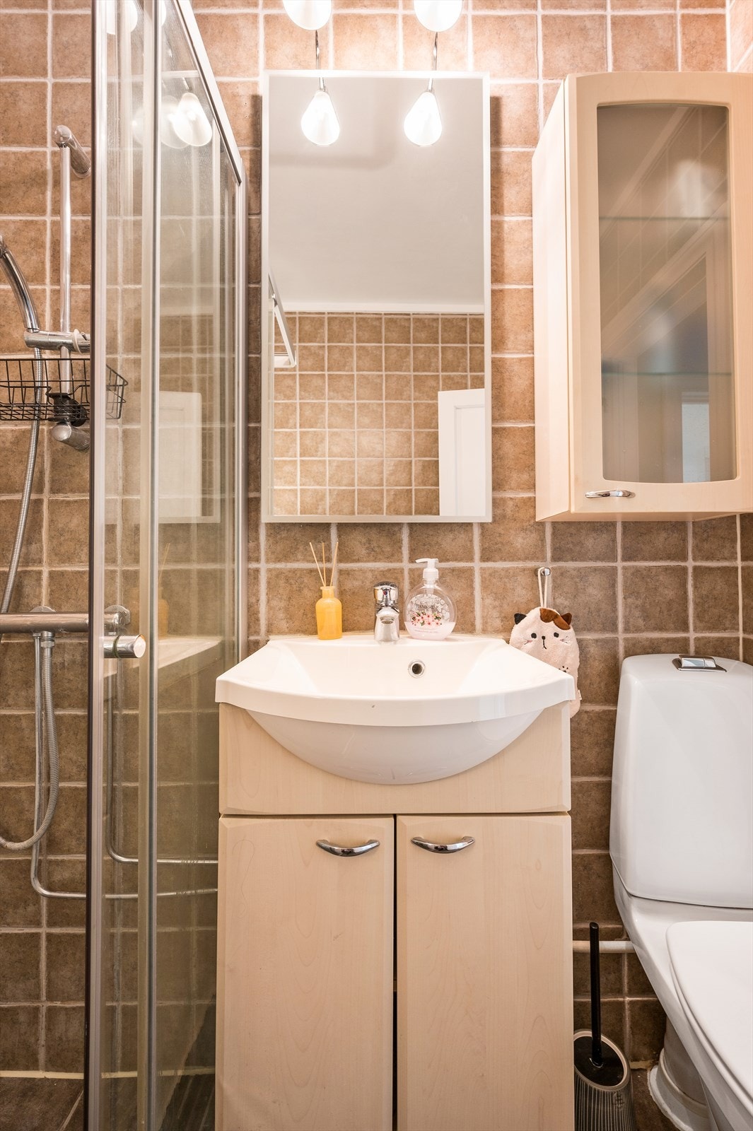 Badet er utstyrt med dusjnisje og dusjdører med fotlist, servant med ett-greps blandebatteri, og gulvstående toalett Galleribilde