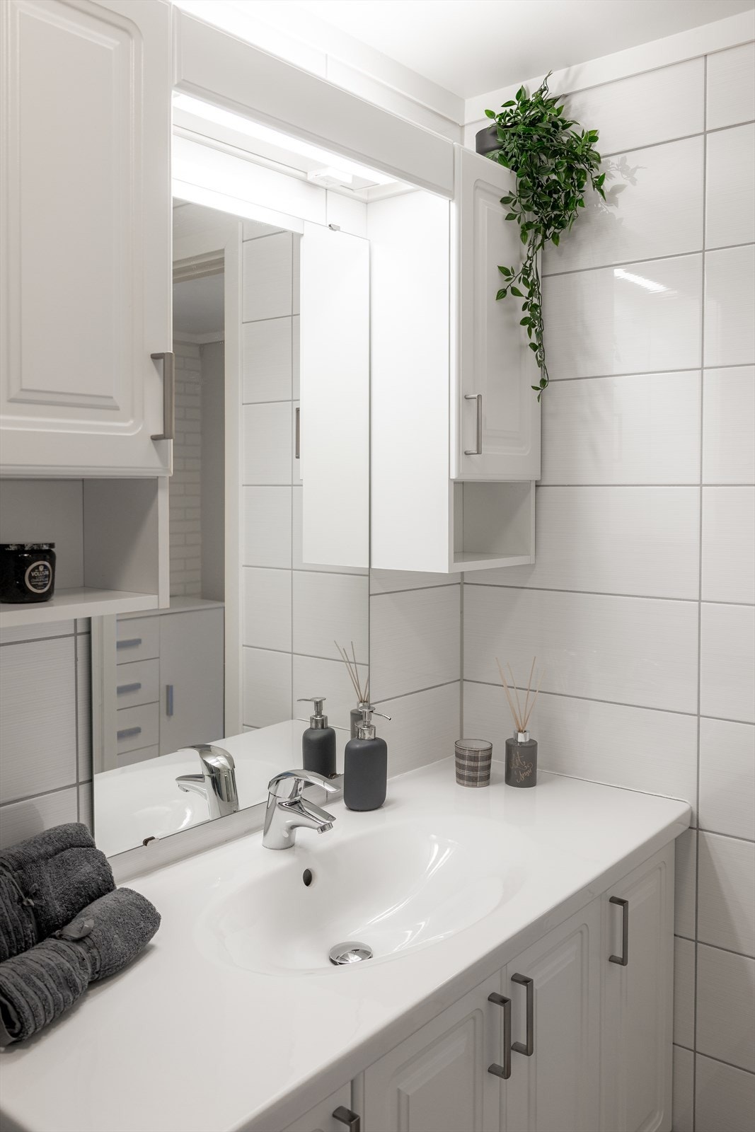 Romslig servantskap med fronter i profilert utførelse og heldekkende servantplate. Speil og overlys med el-stikk, samt to sideskap med ytterligere plass til oppbevaring av baderomsartikler. Galleribilde