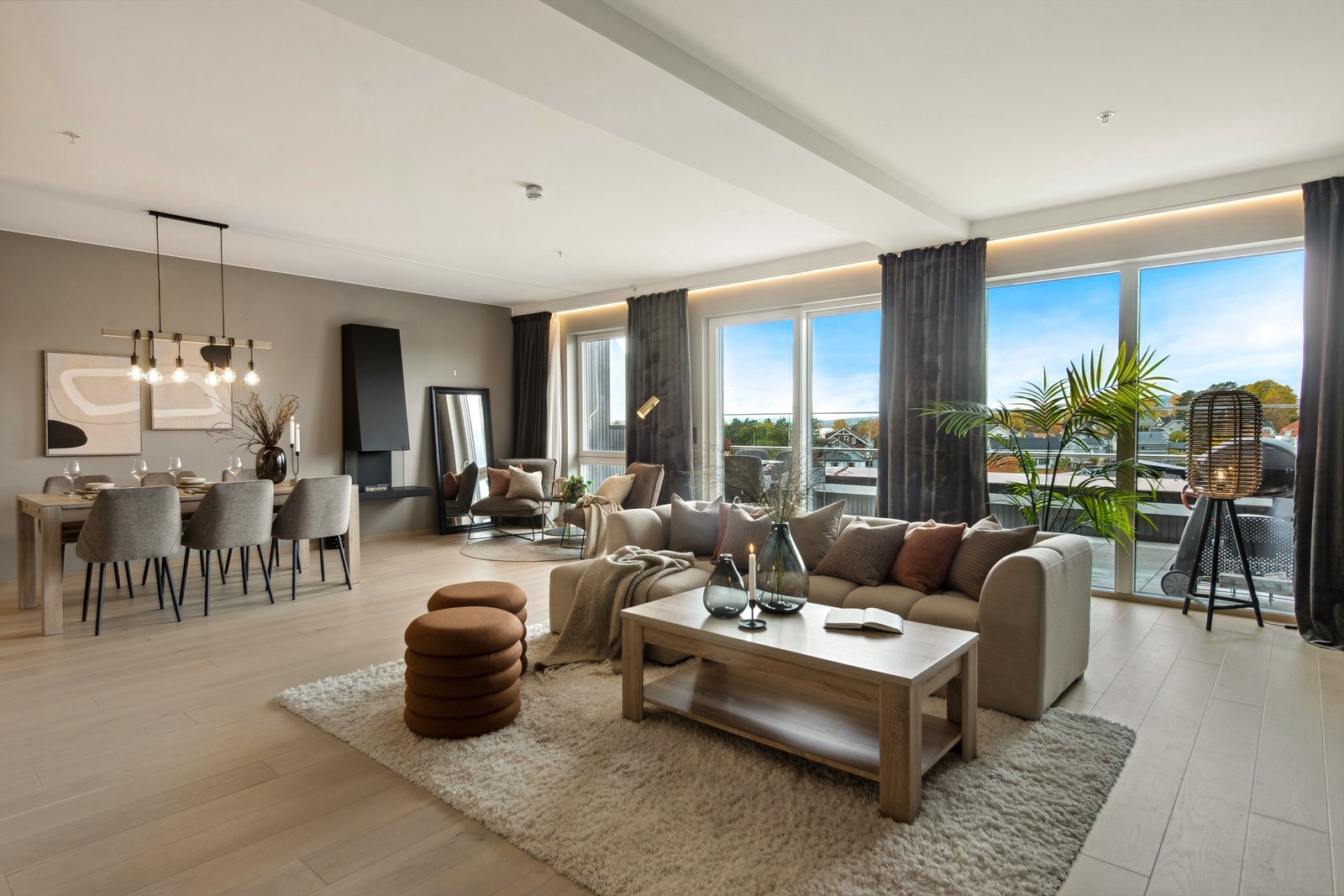 Lys og romslig stue med en lun og tidsriktig fargepalett. De store vinduene ut mot balkongen slipper rikelig med dagslys inn i rommet. Galleribilde