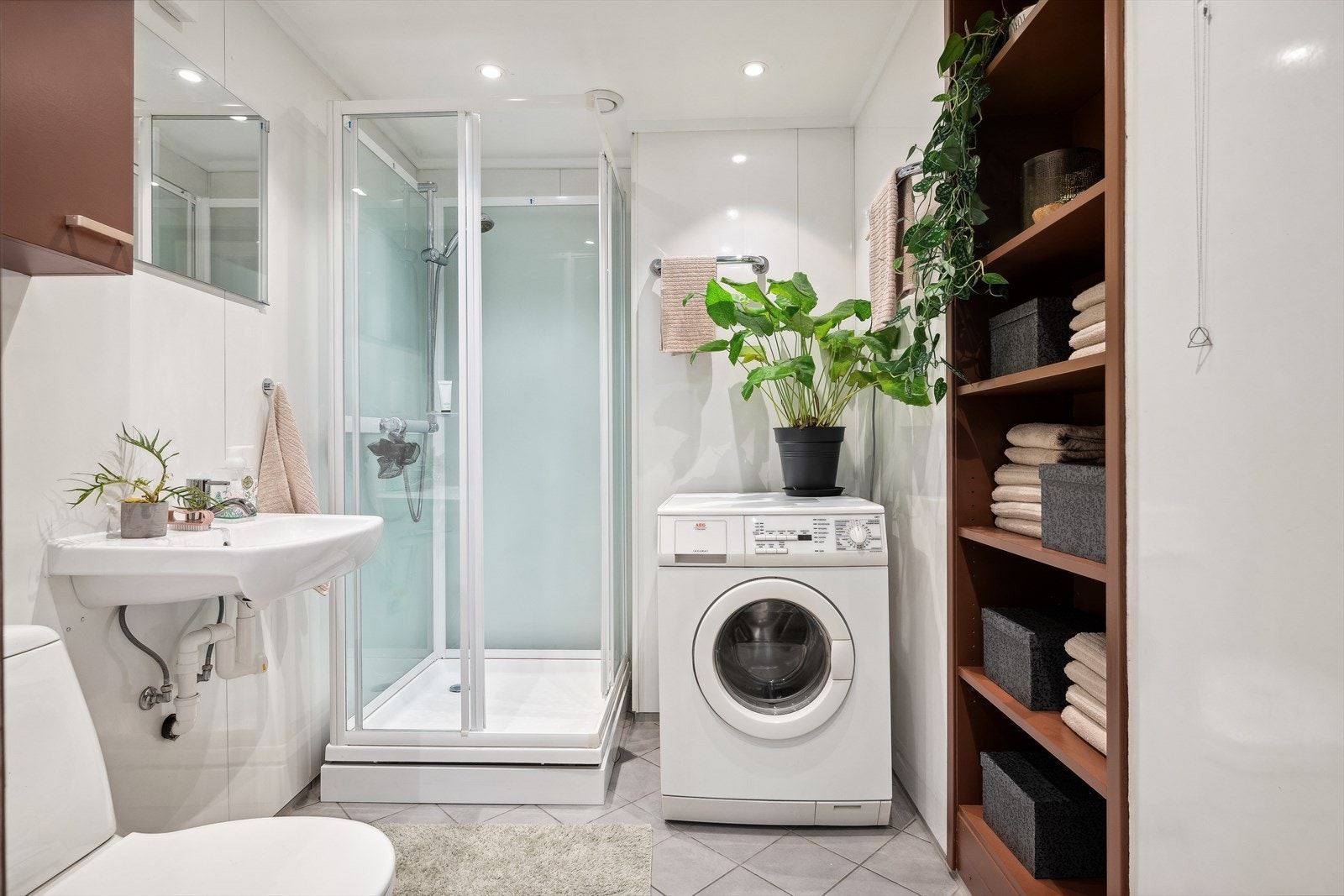 Lyst og delikat baderom med dusjkabinett, ny servant (2024), klosett og opplegg for vaskemaskin. Galleribilde