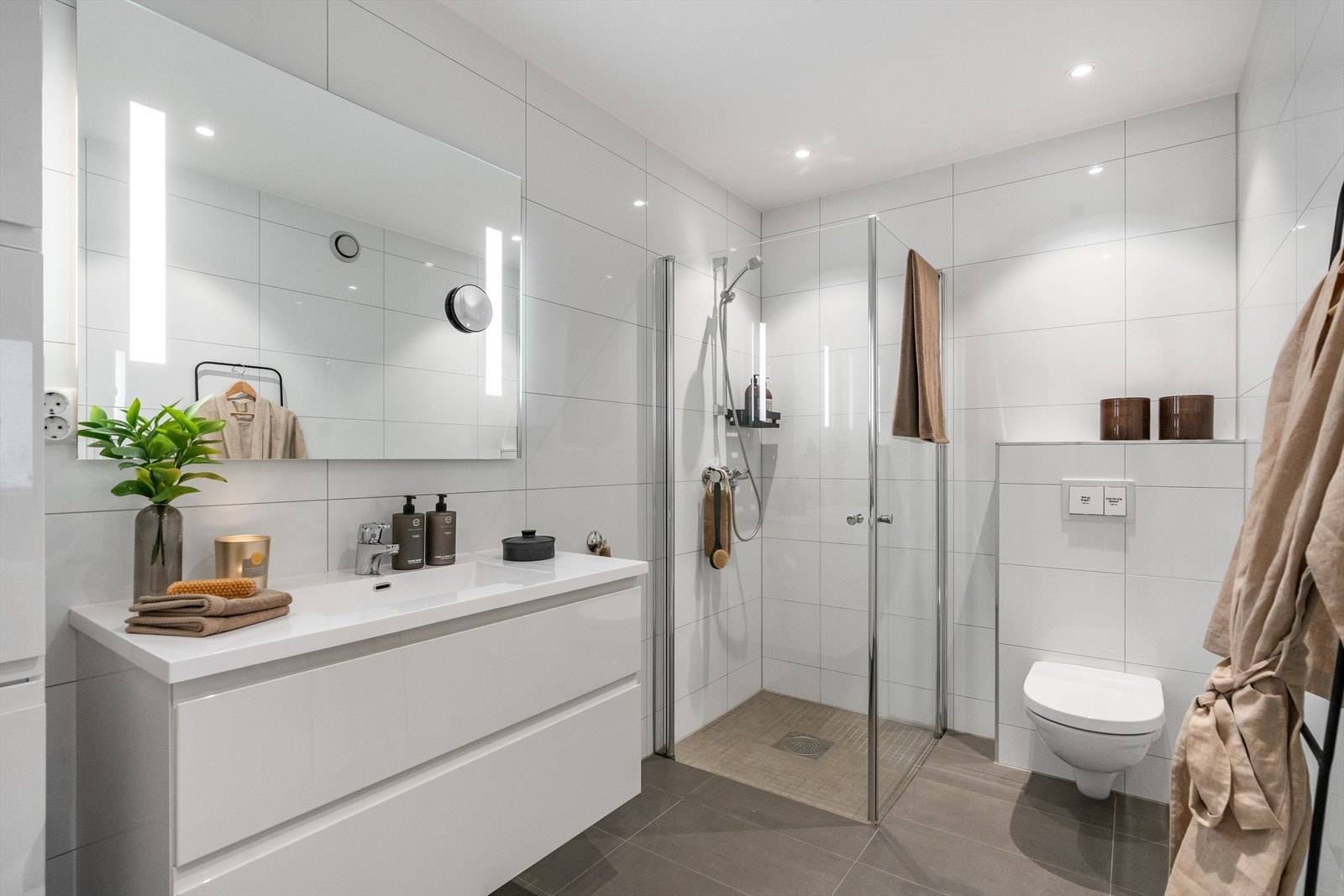 Lekkert bad i 2. etasje med grå fliser på gulv, varmekabler og hvite fliser på vegg. Galleribilde