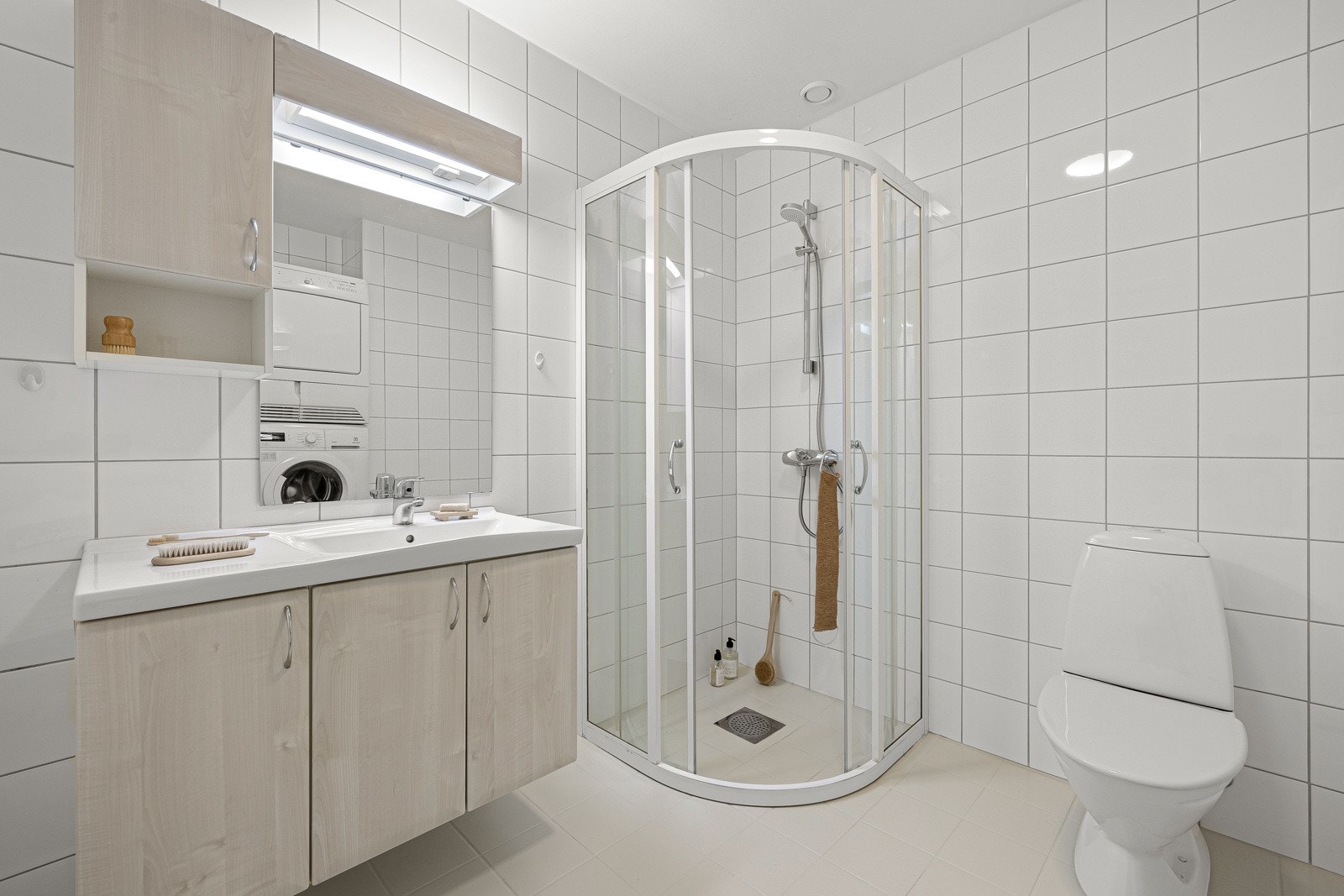 Badet er innredet med dusjhjørne, opplegg for vaskemaskin, toalett og varmtvanntank. Galleribilde