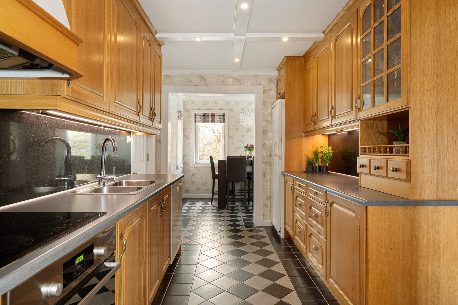 Kjøkkeninnredningen fra 2002 har profilerte fronter og laminat benkeplate med fliser over benk - Integrert platetopp og stekeovn Galleribilde