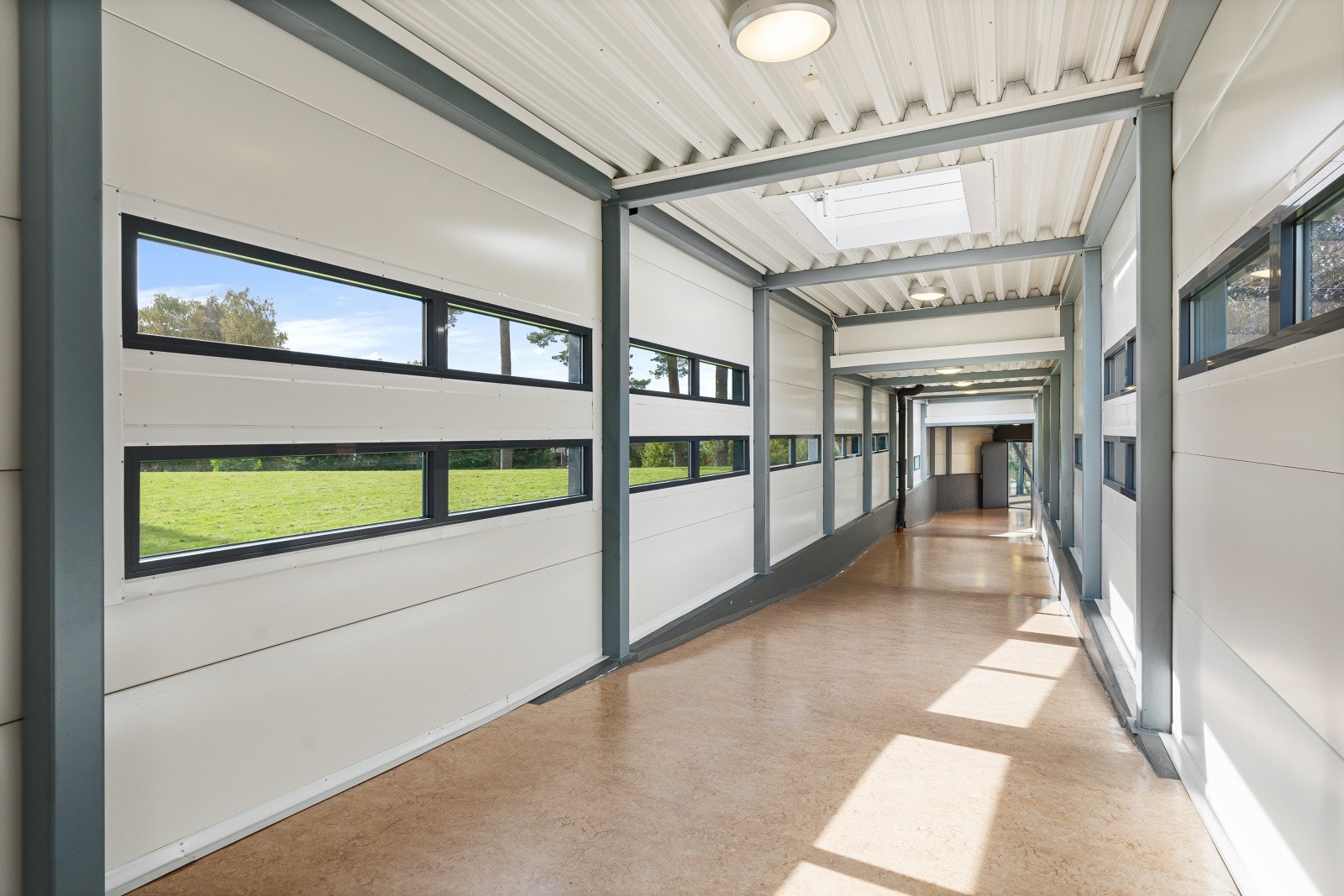 Overbygd tunnel mellom byggene for å kunne gå tørrskodd til kantine, treningsrom o.l Galleribilde