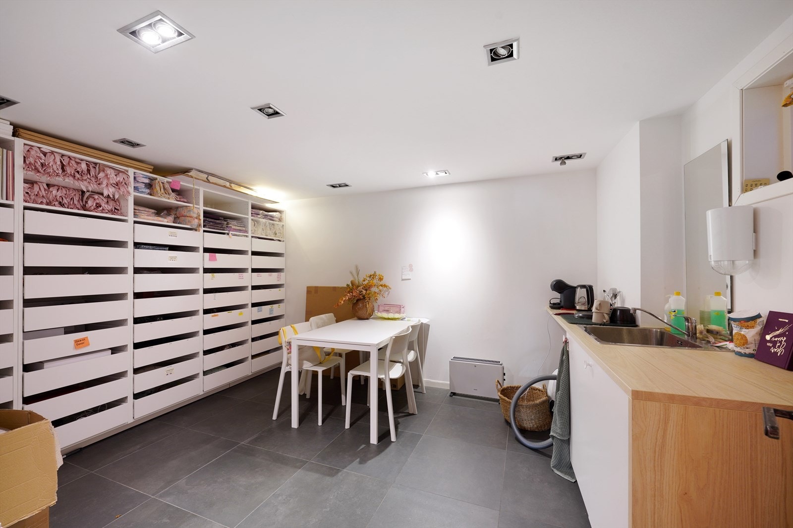 Lyst og romslig bakrom i butikk med lagringsmuligheter og praktisk kjøkkenkrok. Galleribilde