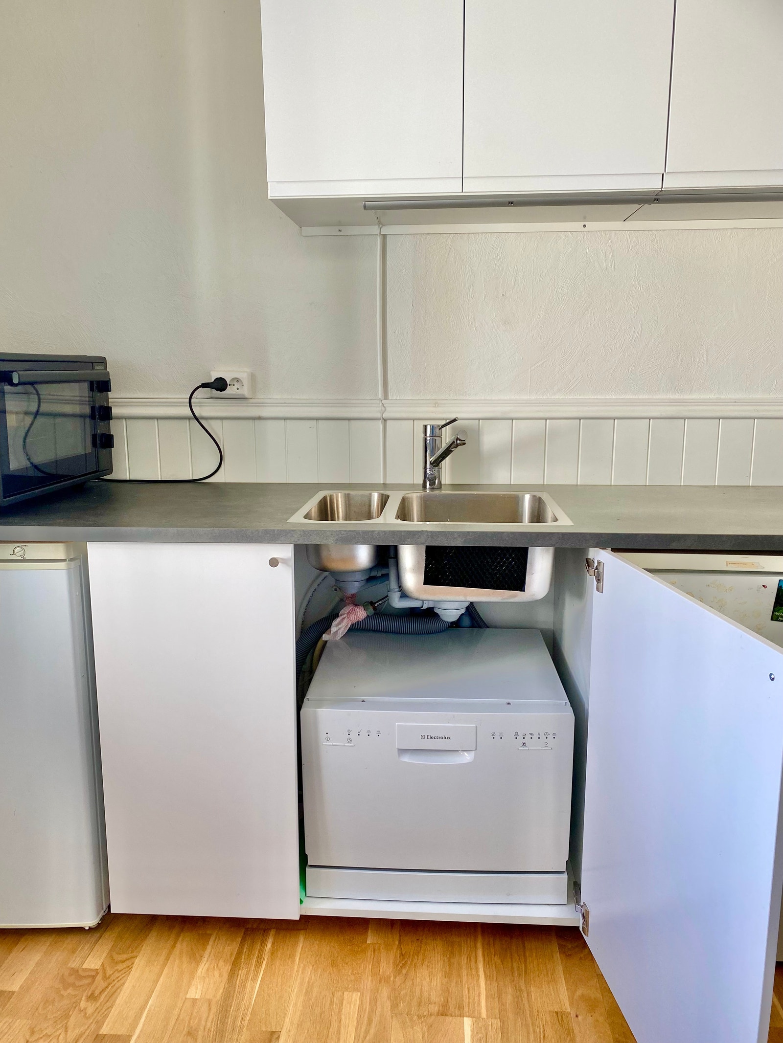 Kjøkken med hybelkomfyr, liten oppvaskmaskin, fryser og kjøleskap Galleribilde