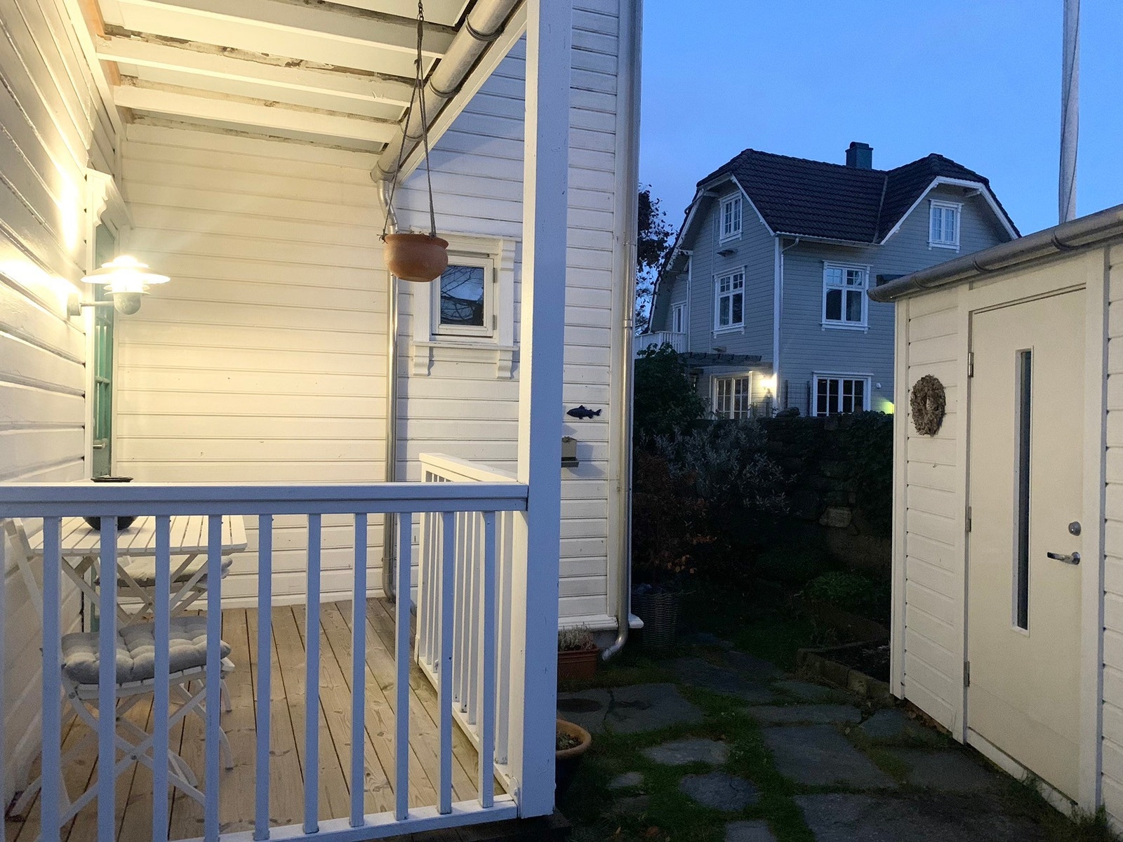 Uteområdet med hyggelig terrasse. Her kan man nyte en kaffekopp i gode solforhold med utsikt mot frodig blomsterbed på sommerstid. Bod til høyre. Galleribilde