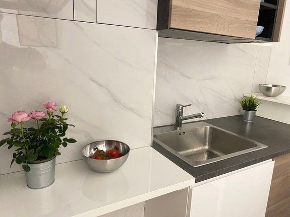 Kjøkkenet fremstår som moderne og nyoppusset med lekre fliser og har en arealeffektiv løsning. Galleribilde