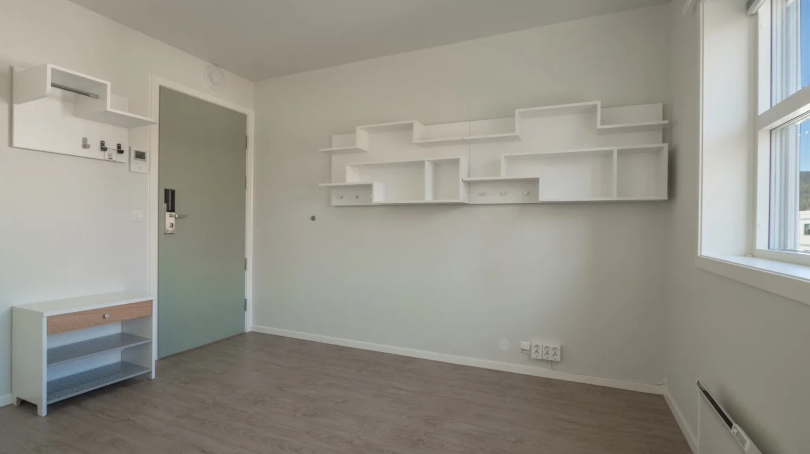 Pulten er plassert under hylla, inntil veggen med vindu. Galleribilde