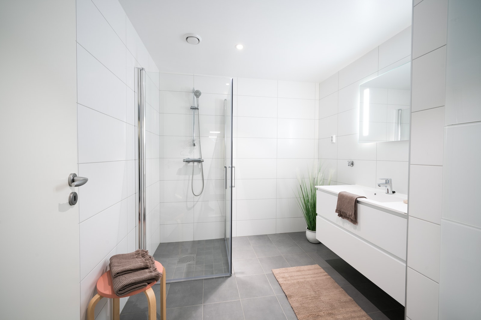 Moderne flislagte bad med tidløs innredning fra JKE. Innfellbare glassdører i dusj. Vegghengte toalett. Galleribilde